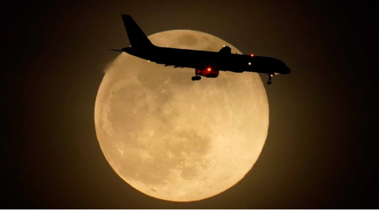 An airplane flies by as supermoon rises in Kentucky, USA.