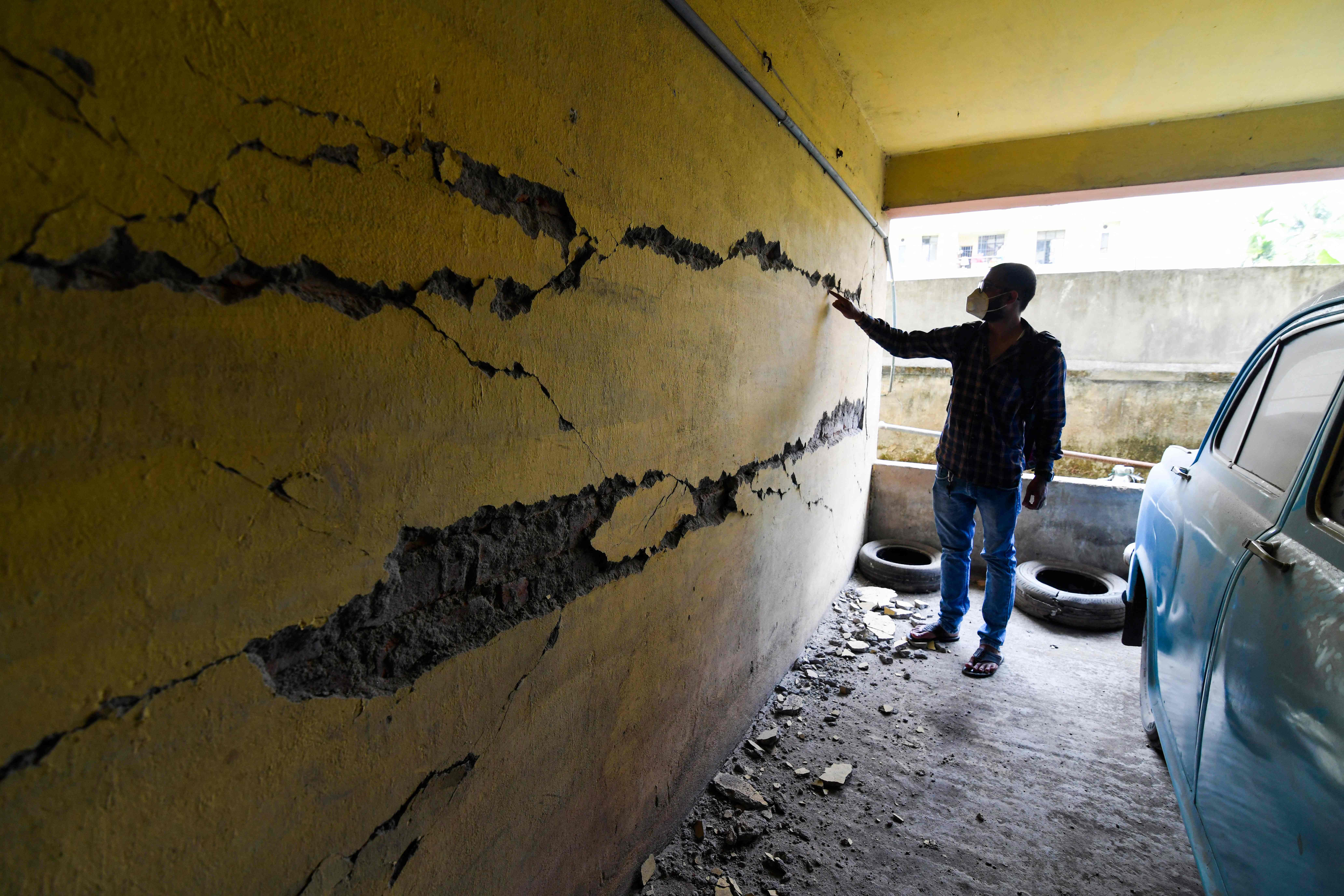 A man looks at cracks on a wall at an apartment building in Guwahati on April 28, 2021, after a strong earthquake hit Assam in northeastern India, damaging buildings.