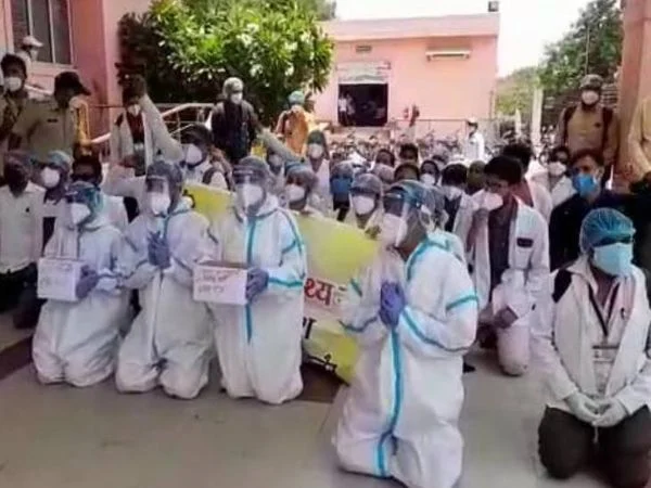 Healthcare workers kneel before collector outside Government Charak Hospital.