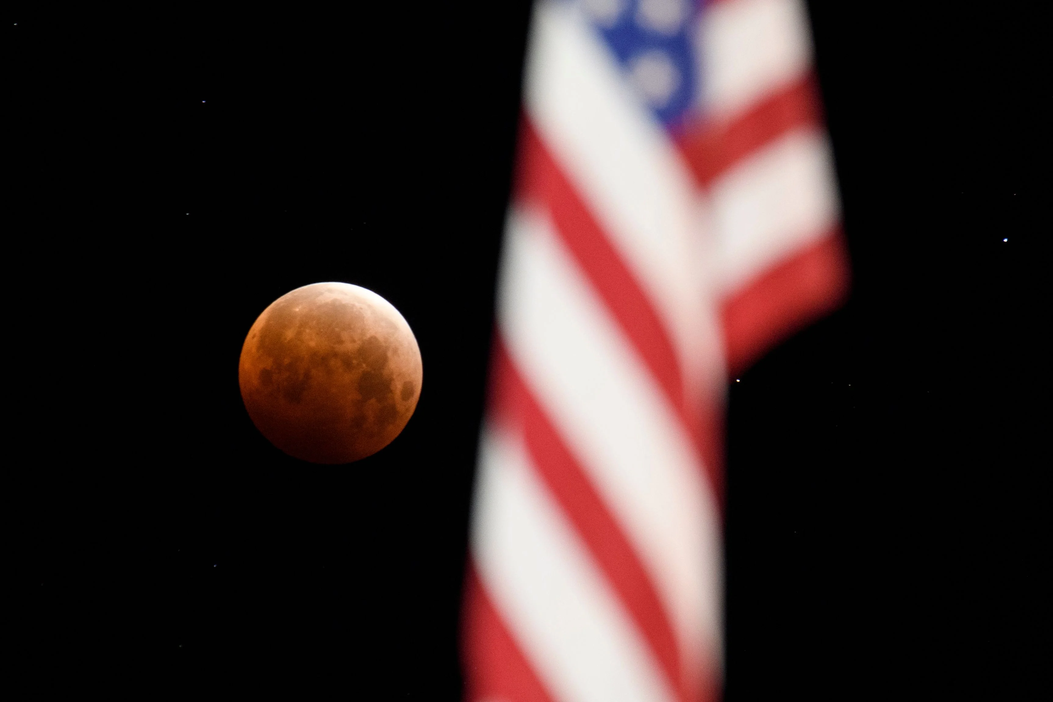 A full moon is seen framed with a US flag during totality of a total lunar eclipse as the moon enters Earths shadow for a "Super Blood Moon" on May 26, 2021 in Chico, California.