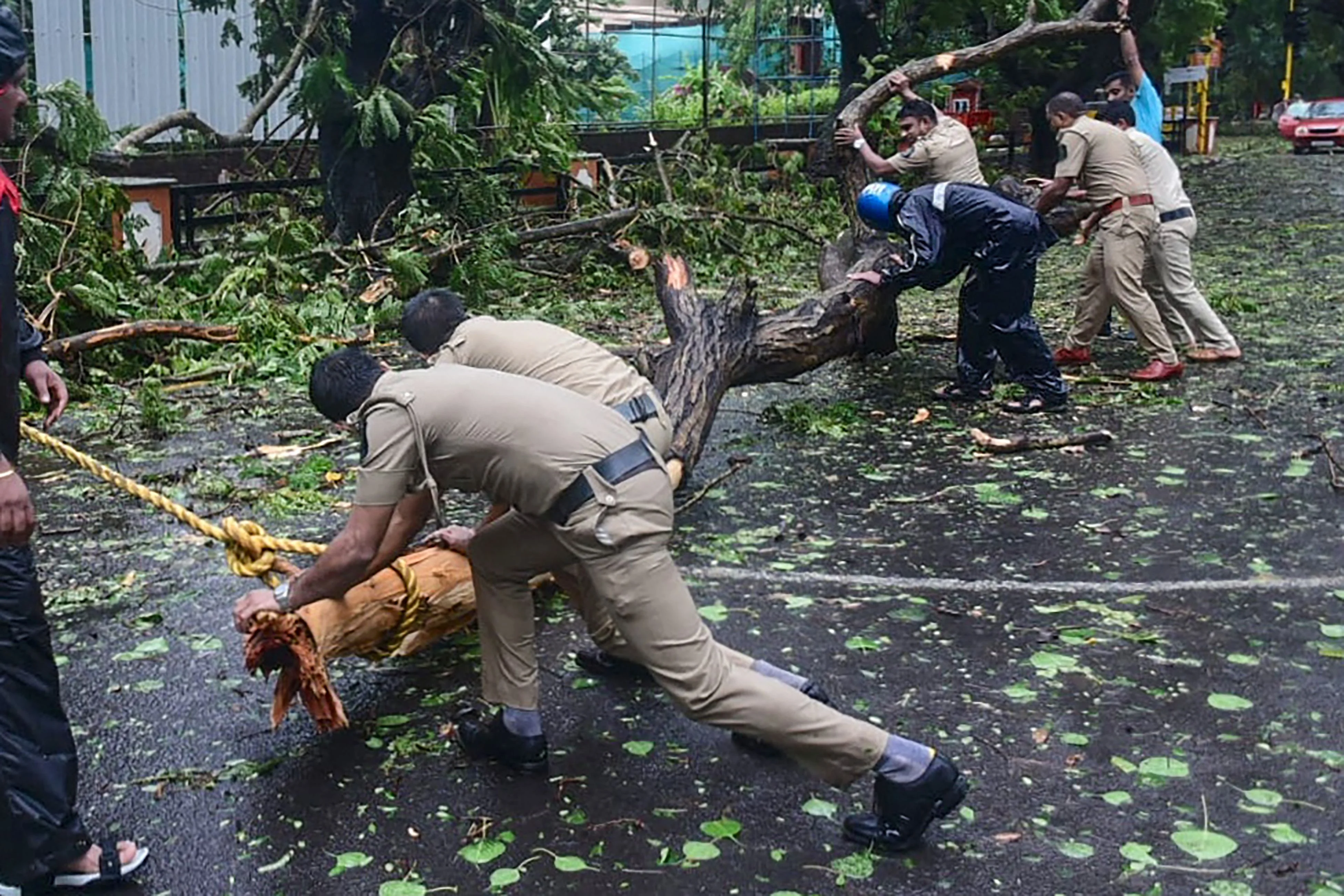 Police personnel clear fallen trees from a road following severe cyclonic storm Tauktae, at Panjim in Goa on May 16, 2021.