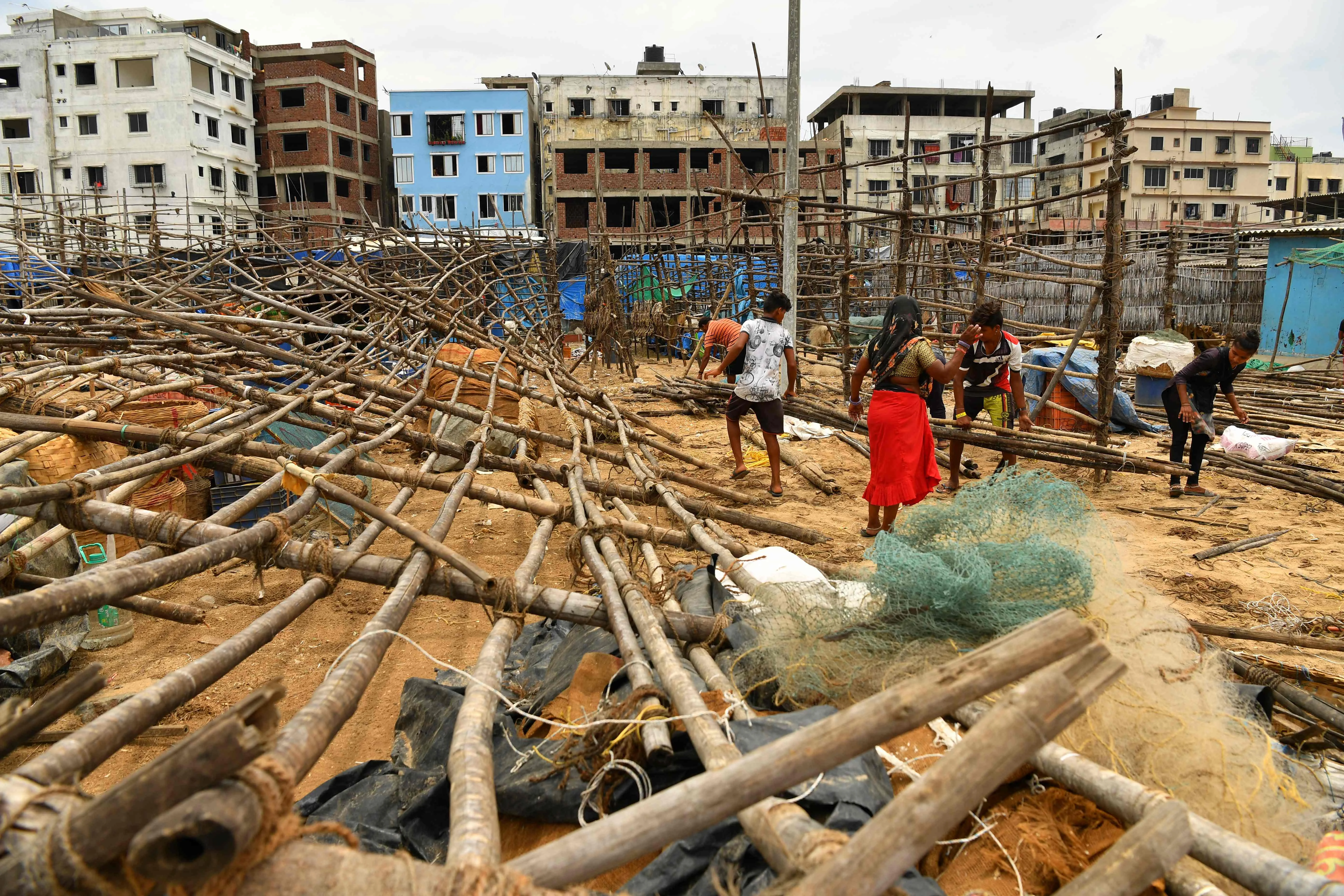 Fisherfolk mend bamboo racks being used to dry fishes after they were brought down by strong winds caused by the impending cyclone Tauktae at a fishing village off the city coast in Mumbai on May 16, 2021.