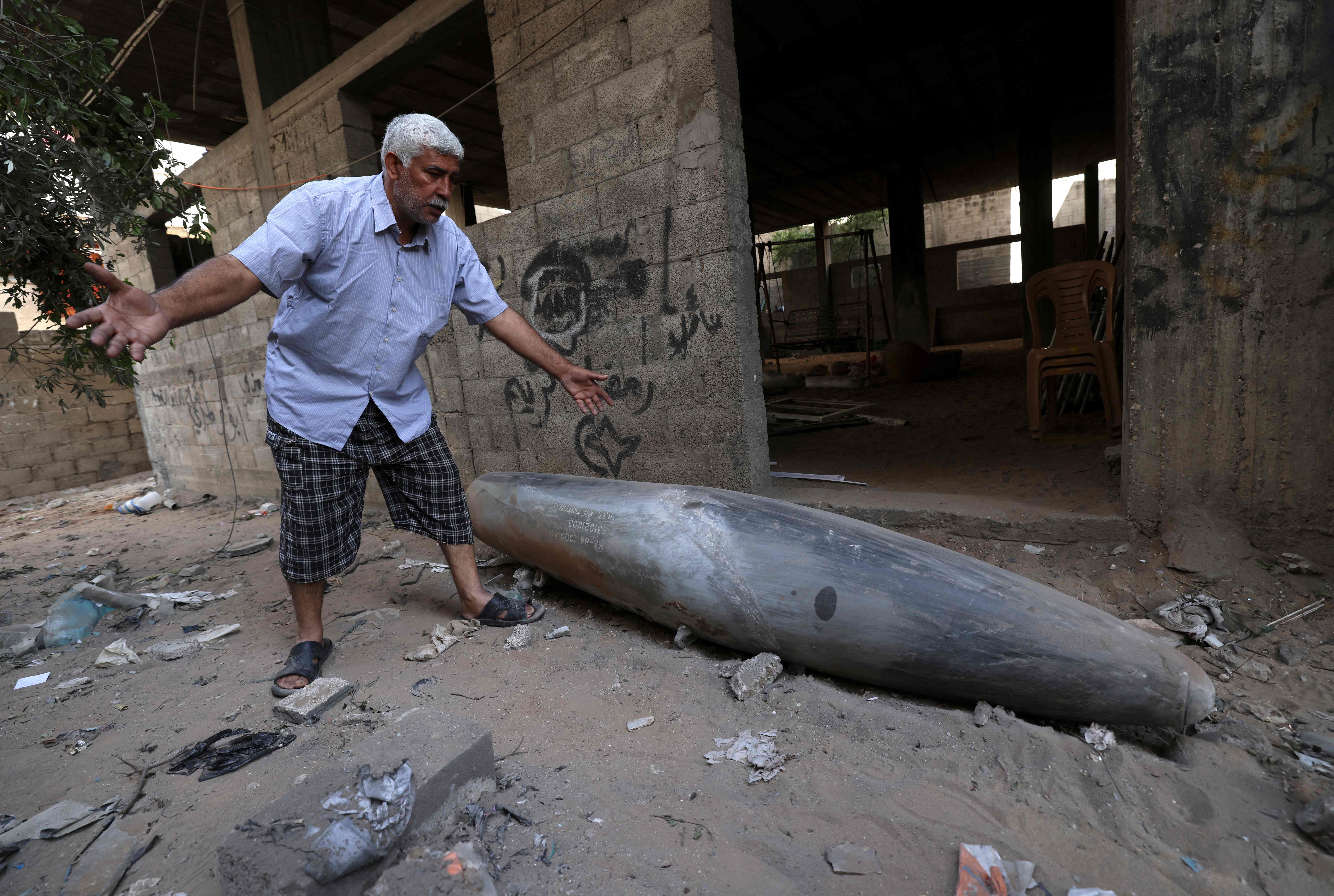 A Palestinian man reacts as he looks at an unexploded bomb dropped by an Israeli F-16 warplane on Gaza Citys Rimal neighbourhood on May 18, 2021. - The UN Security Council was due to hold an emergency meeting today amid a flurry of urgent diplomacy aimed at stemming Israel air strikes that have killed more than 200 Palestinians.