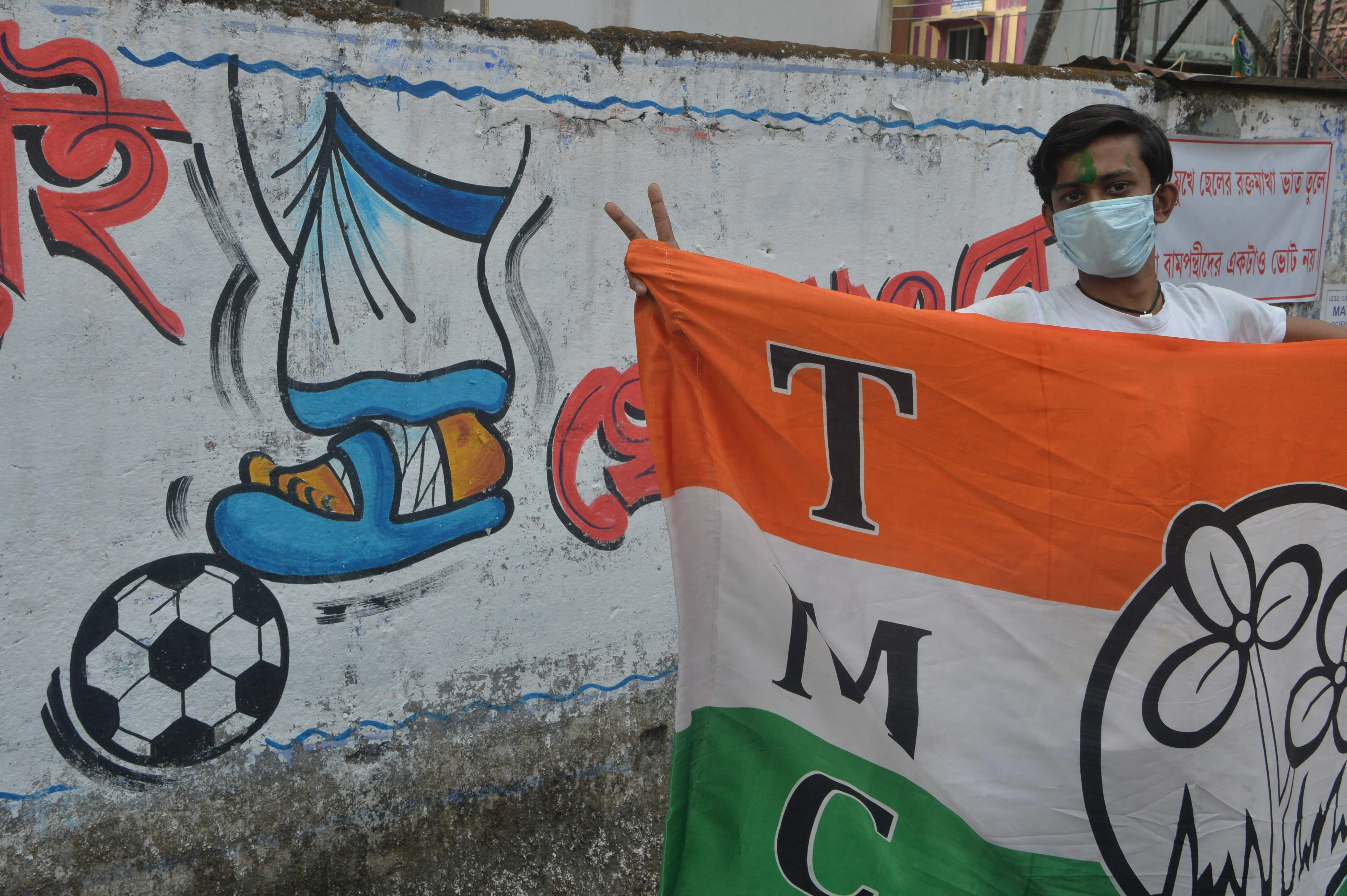 Indian supporters of the All India Trinamool Congress (AITC) celebrate the party's lead in front of a mural depicting the injured foot of AITCs leader Mamata Banerjee during the ongoing counting process of the West Bengal legislative assembly election, in Siliguri on May 2, 2021.