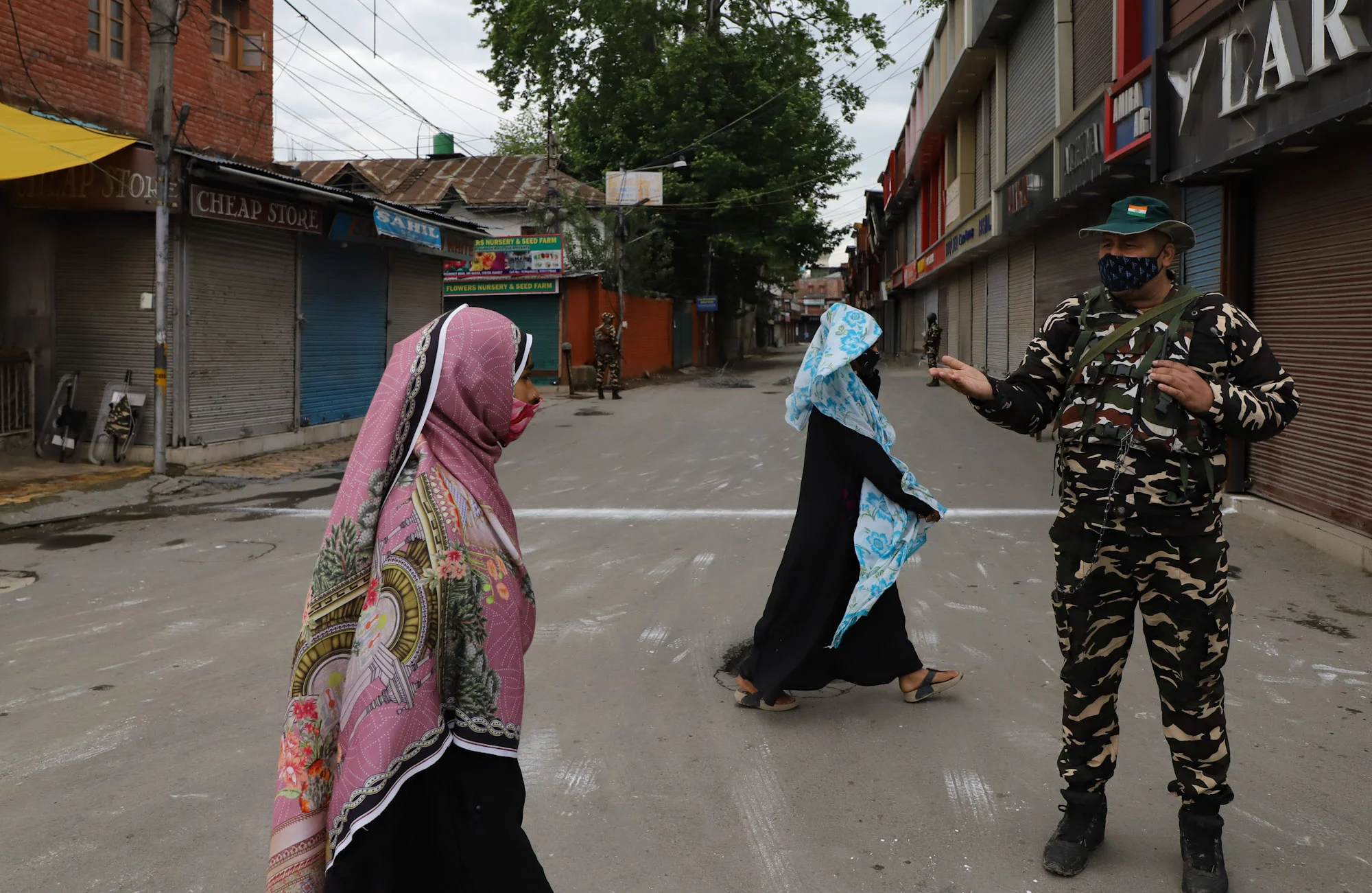 Kashmiri women walk past security personnel on the day of the Muslim festival of Eid ul-Fitr as strict curfew has been imposed amid concerns over the spread of Coronavirus in Srinagar, Kashmir.