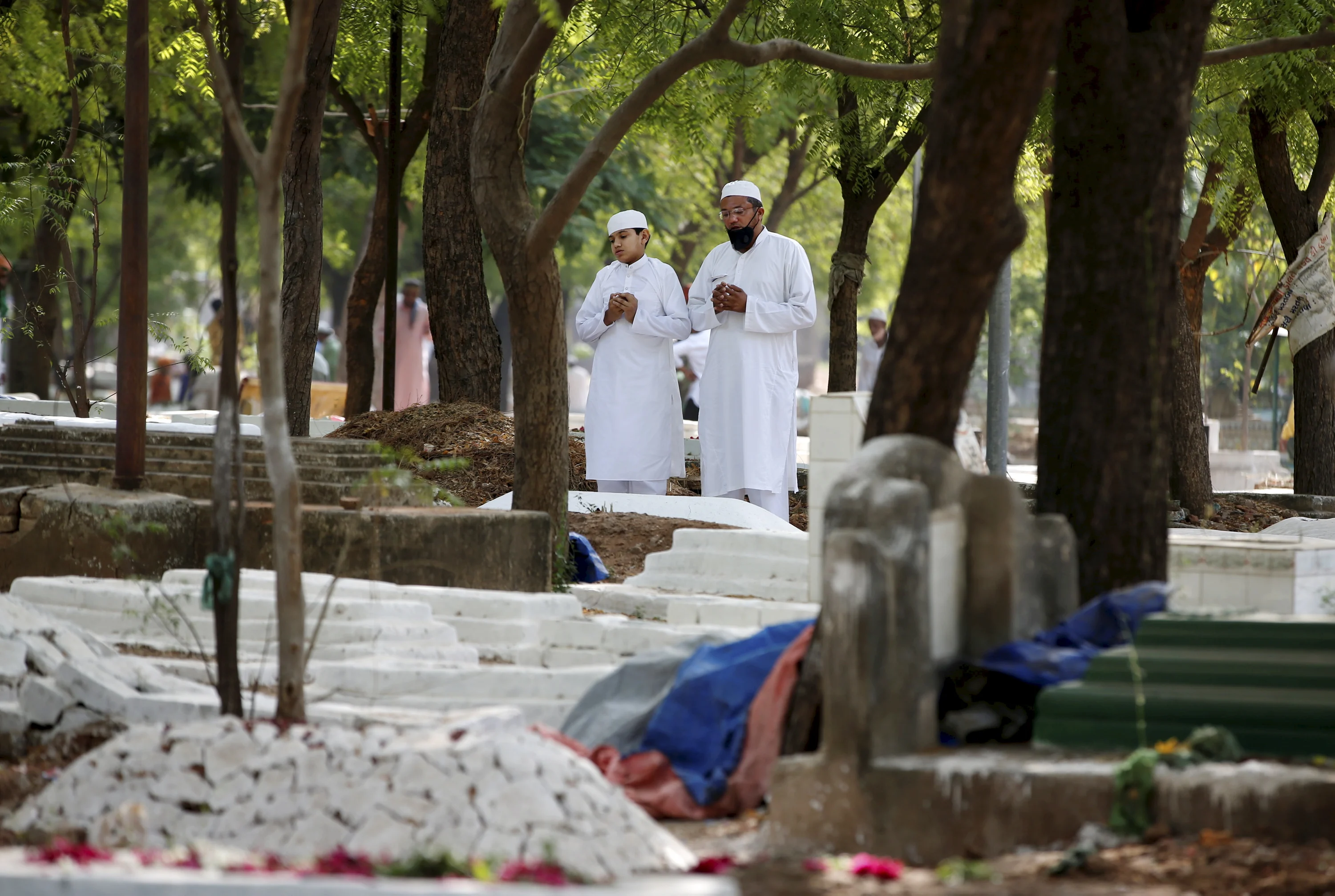 Muslims offer prayers next to the graves of their relatives on the occasion of Eid ul-Fitr, at a graveyard in Ahmedabad, Friday, May 14, 2021.