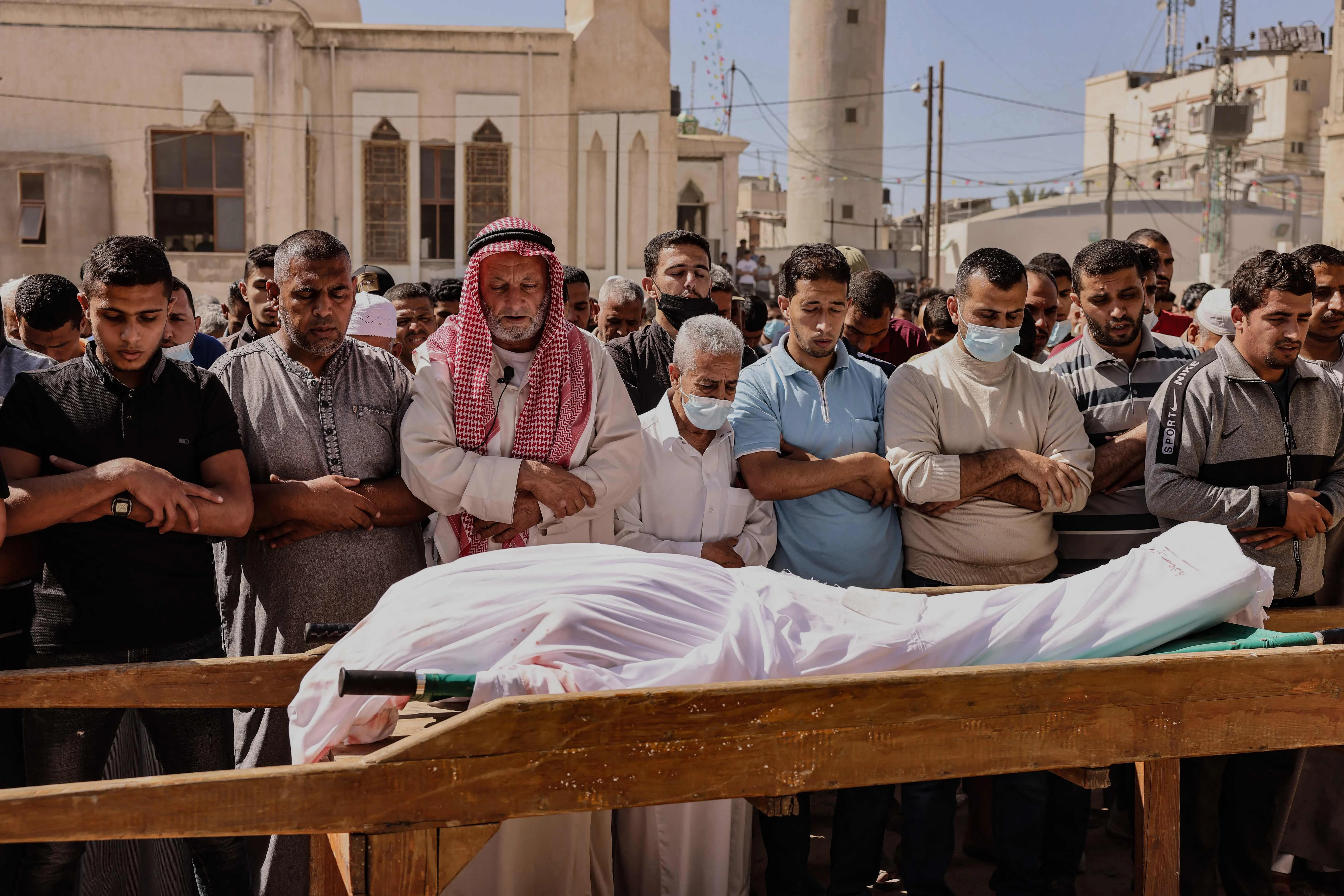 Mourners recite a prayer over the body of Majd Abu Saadahthe, a Palestinian killed in an Israeli airstike, during his funeral in the town of Khan Yunis in the southern Gaza Strip, on May 12, 2021. - Israeli air raids in the Gaza Strip have hit the homes of high-ranking members of the Hamas militant group, the military said Wednesday, with the territorys police headquarters also targeted.