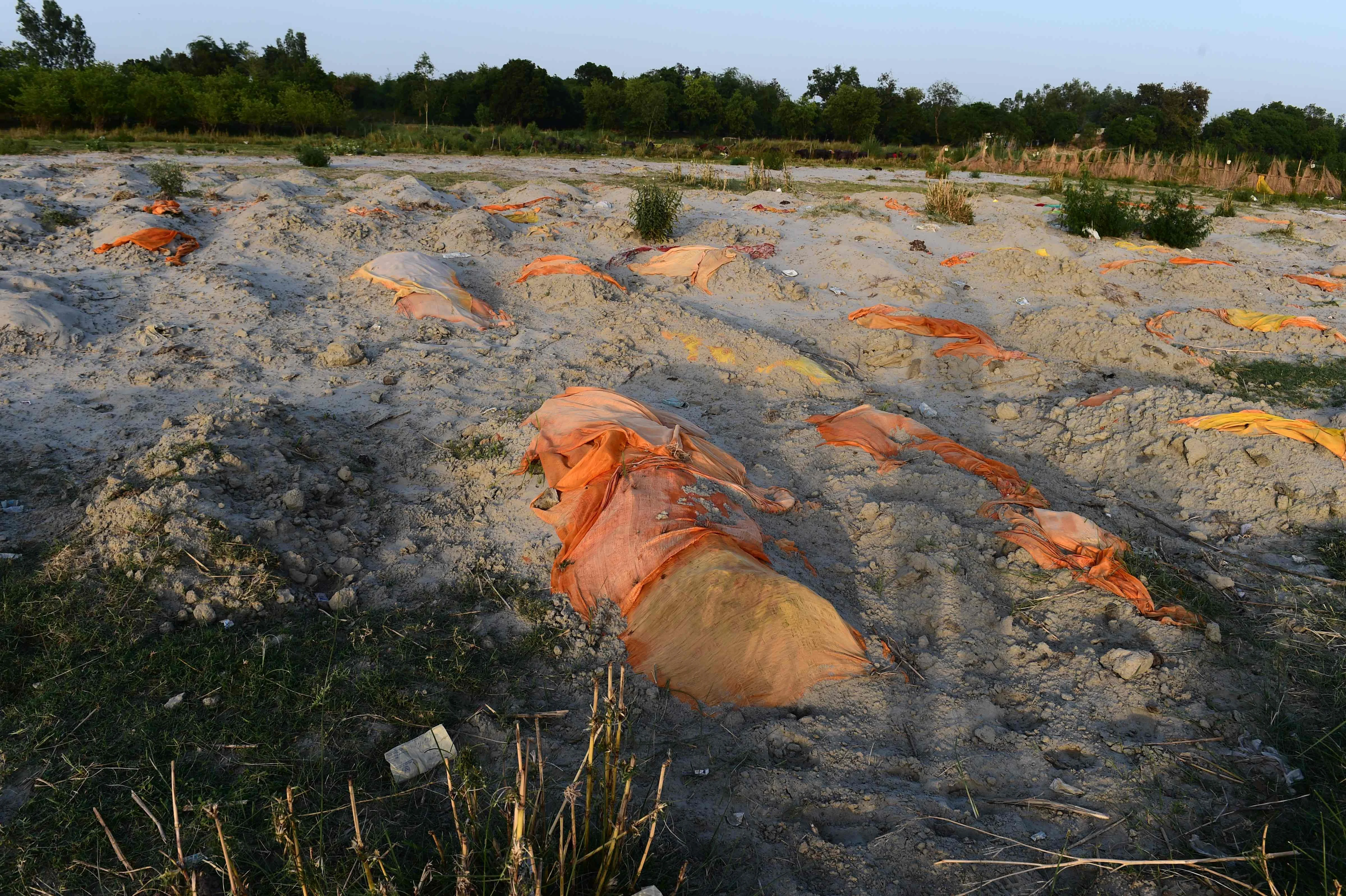 Bodies of suspected Covid-19 coronavirus victims are seen partially buried in the sand near a cremation ground on the banks of Ganges River in Rautapur Ganga Ghat, in Unnao