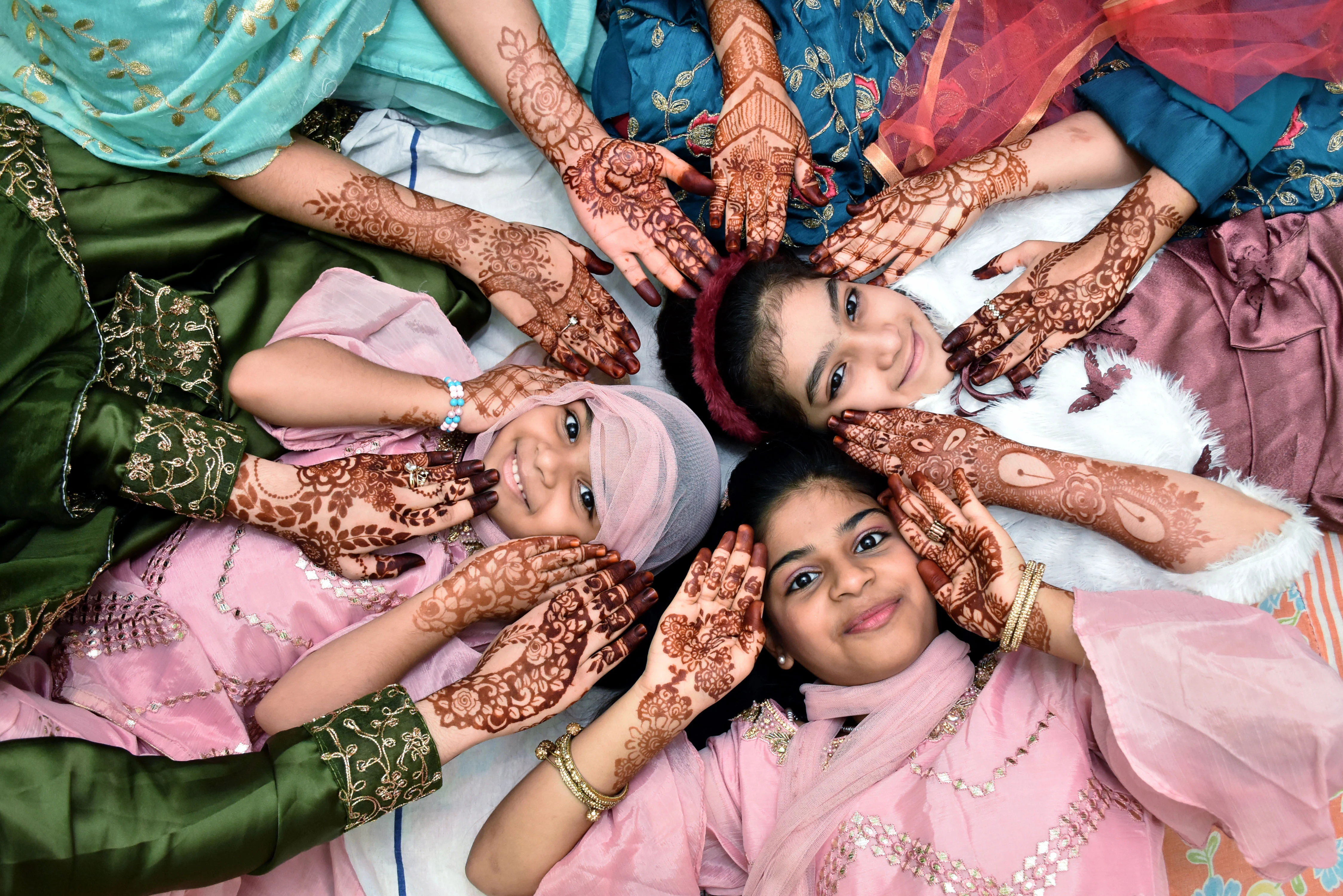 Girls pose for a photograph with Heena design on their hand during Eid-ul-Fitr festival marking the end of the holy fasting month of Ramadan, in Hyderabad on Friday.