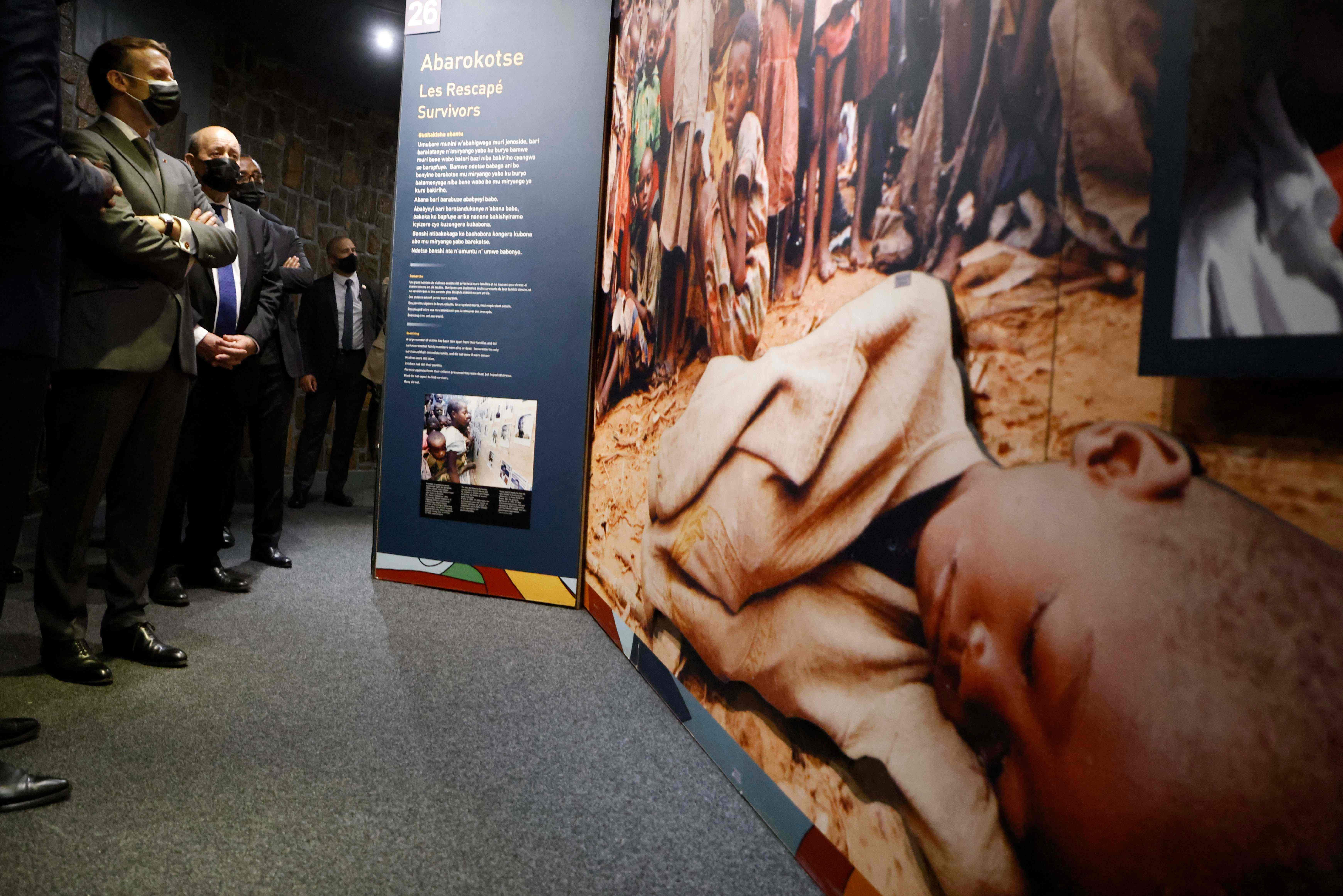 Macron (L) and French European and Foreign Affairs Minister Jean-Yves Le Drian stop to look at images during their visit to the Kigali Genocide Memorial, where some 250,000 victims of the massacres are buried, in Kigali on May 27