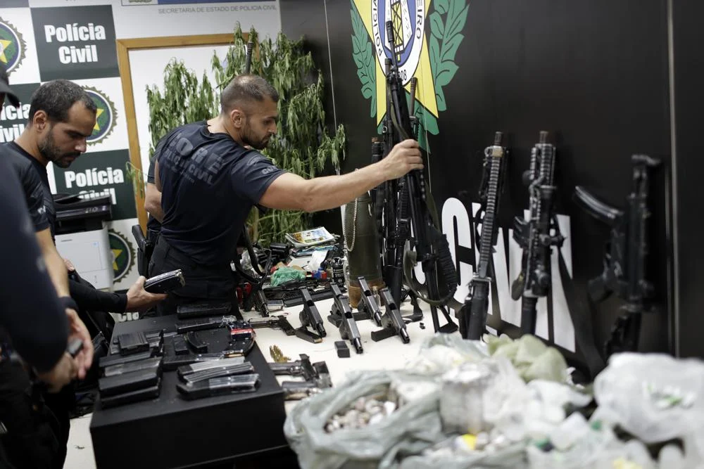 Policemen collect the drugs and weapons, allegedly seized during a police operation against drug dealers in Jacarezinho slum