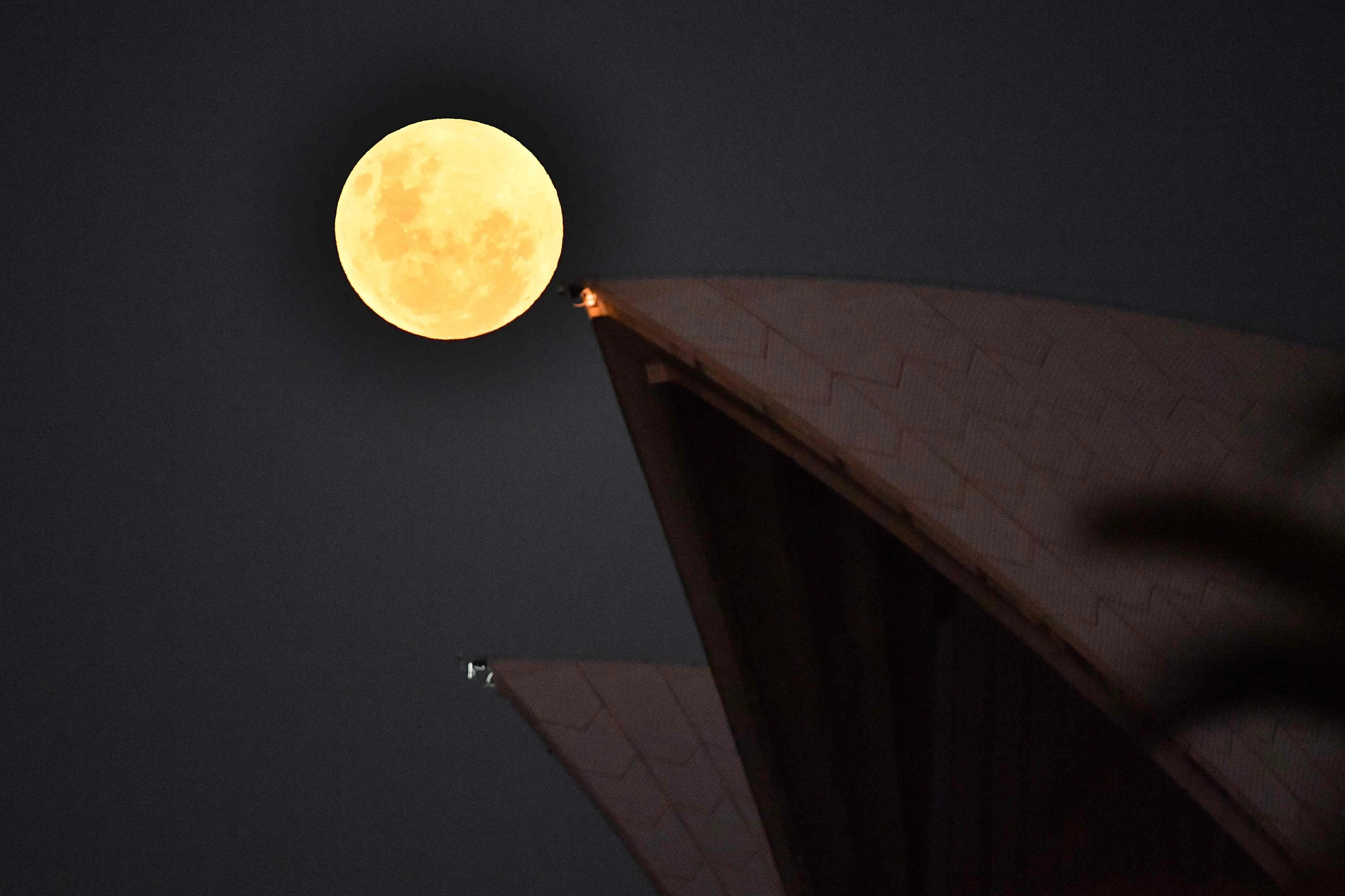 The Moon rises over the Opera House in Sydney on May 26, 2021, ahead of a total lunar eclipse as stargazers across the Pacific are casting their eyes skyward to witness a rare "Super Blood Moon".