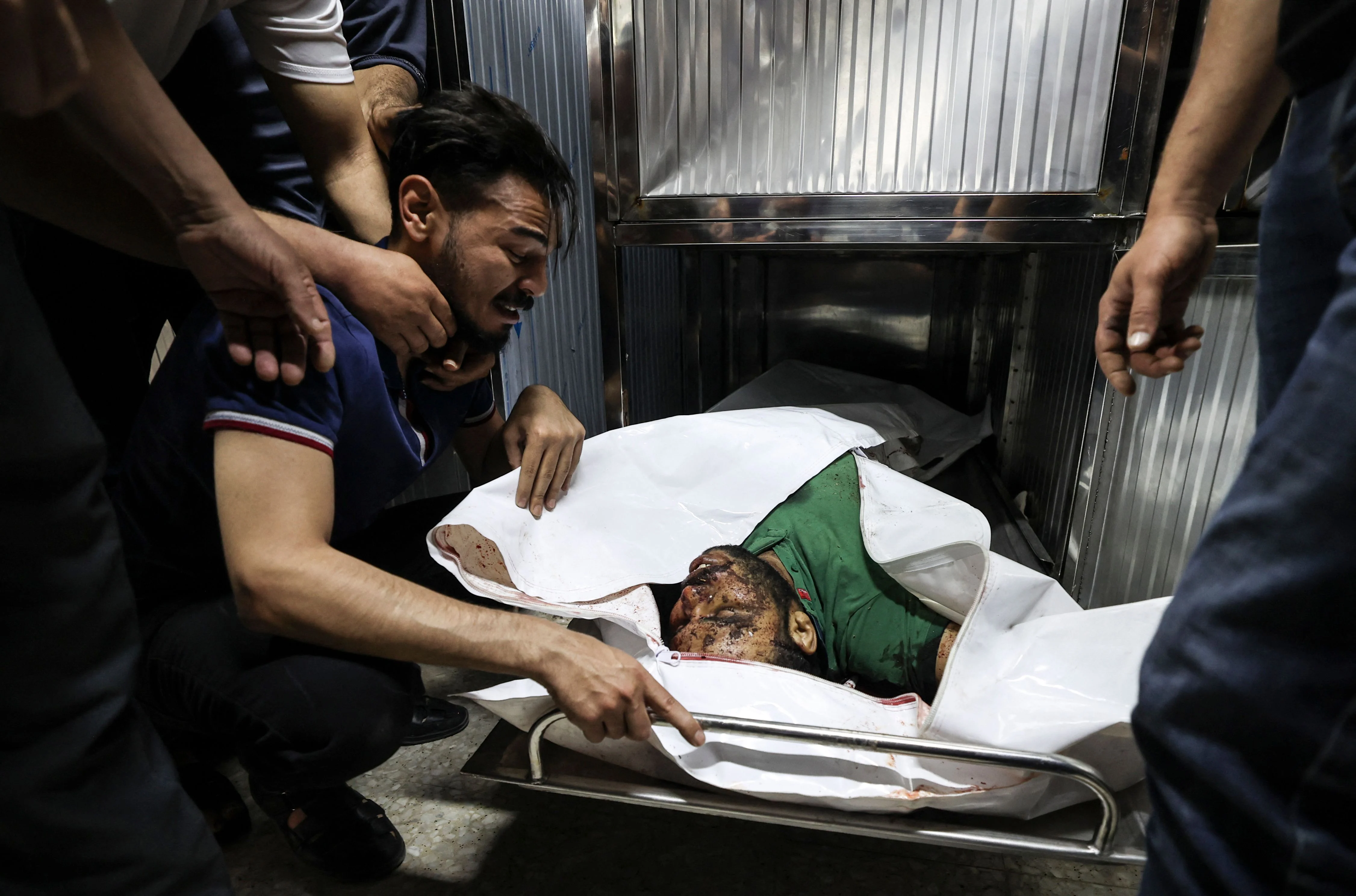 A Palestinian mourns over the body of a relative in the mortuary of Al-Shifa Hospital in Gaza city following Israeli airstrikes on targets in the Gaza Strip, on May 12, 2021, amid the most intense Israeli-Palestinian hostilities in seven years. - Israels Defence Minister Benny Gantz vowed more attacks on Palestinian militant groups in Gaza to bring "total, long-term quiet" before considering a ceasefire.