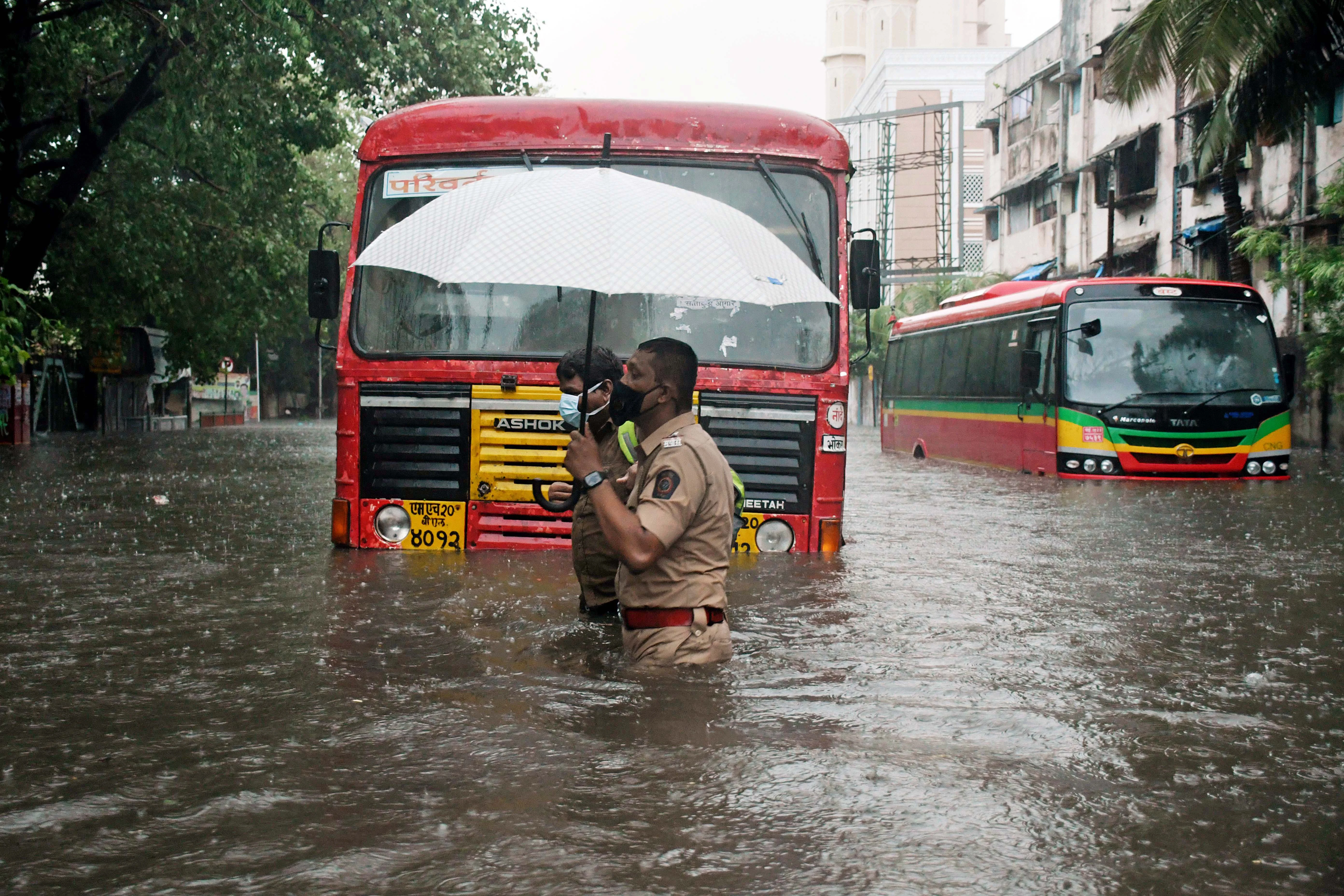 Police personnel carries an umbrella as he wades through a waterlogged street after heavy rainfall and strong winds triggered by Cyclone Tauktae, in Mumbai on Monday.