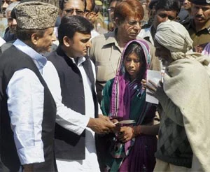 Uttar Pradesh CM Akhilesh Yadav presents a cheque to the family of slain village head Nanhe Yadav at Balipur village in Kunda, Pratapgarh.