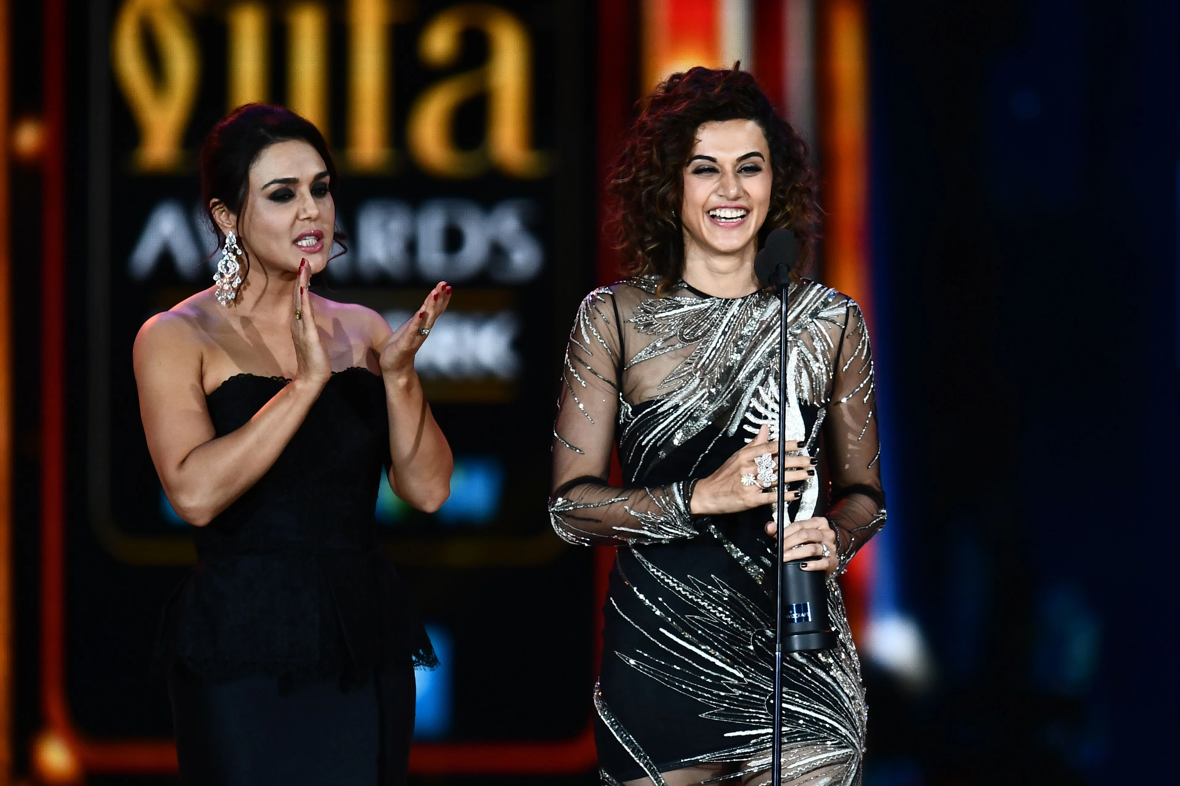 Bollywood actress Taapsee Pannu (R) accepts Women of the Year award from Preity Zinta (L) during IIFA award of the 18th International Indian Film Academy (IIFA) Festival at the MetLife Stadium in East Rutherford, New Jersey, on July 15, 2017. / AFP PHOTO / JEWEL SAMAD