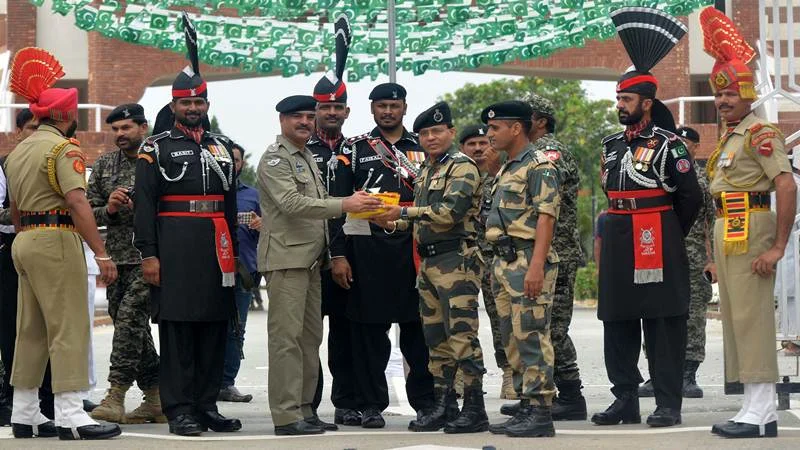 Pakistani Wing Commander Bilal (4L) presents sweets to Indian Border Security Force (BSF) Commandant Sudeep (4R) during a ceremony to celebrate Pakistan’s Independence Day at the India-Pakistan Wagah border post on August 14, 2017. / AFP PHOTO / NARINDER NANU