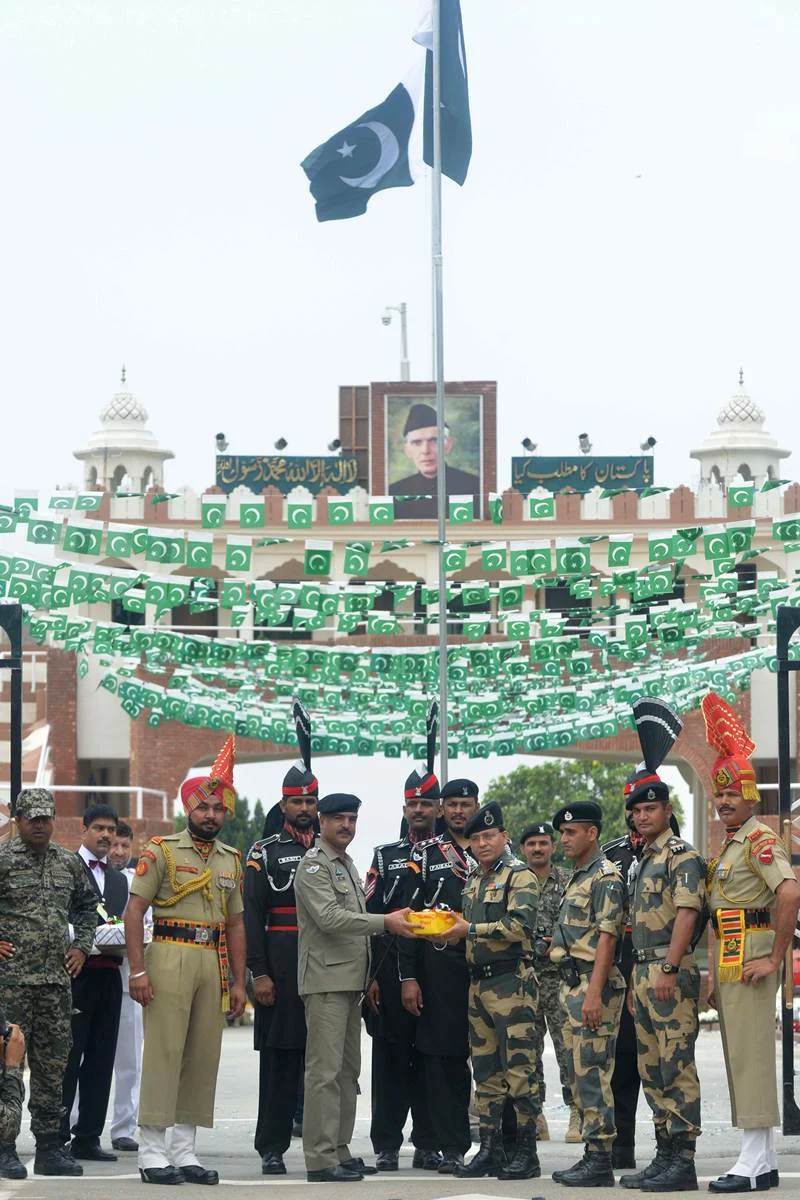 Pakistani Wing Commander Bilal (5L) presents sweets to Indian Border Security Force (BSF) Commandant Sudeep (5R) during a ceremony to celebrate Pakistan’s Independence Day at the India-Pakistan Wagah border post on August 14, 2017. / AFP PHOTO / NARINDER NANU
