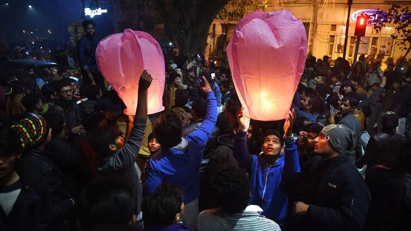Pakistani people prepare to release lanterns as they gather to celebrate the new year in Lahore early on January 1, 2018. / AFP PHOTO / ARIF ALI