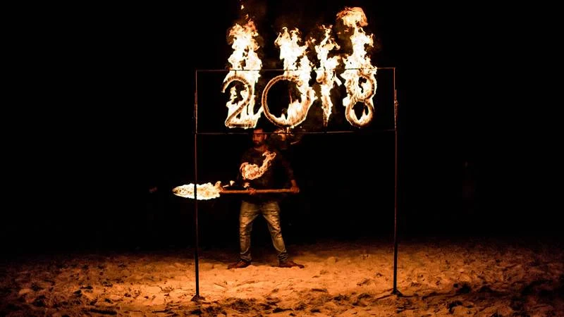 A staff of a hotel lights a sign that reads 2018 during the New Year’s Eve celebration on Nungwi Beach in Zanzibar, Tanzania, on December 31, 2017. / AFP PHOTO / GULSHAN KHAN