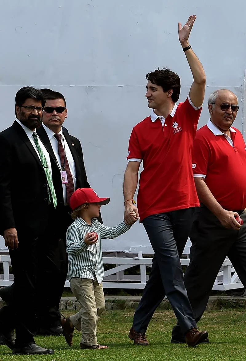 Canadian Prime Minister Justin Trudeau (C) waves as he leaves after a cricket event at a school in New Delhi on February 22, 2018. / AFP PHOTO / MONEY SHARMA