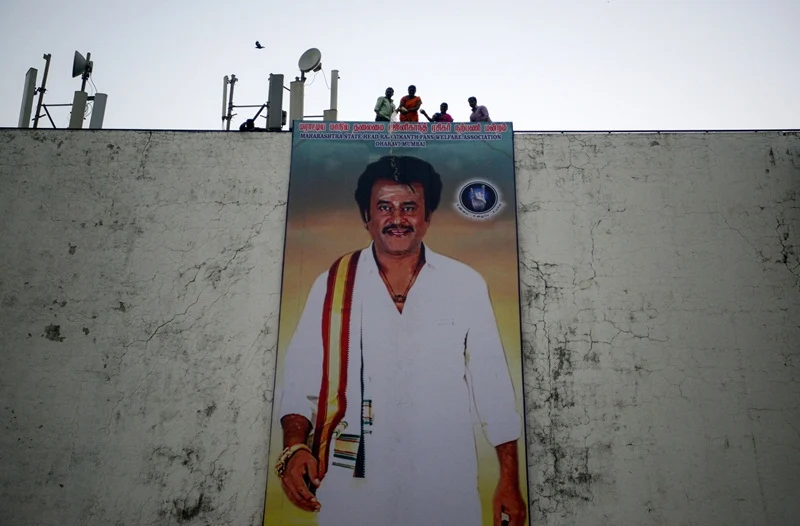 Indian fans pour milk on a huge poster of Bollywood star Rajinikanth put up outside the cinema hall as they celebrate before attending the early morning show of his new Tamil-language film “2.0” on the first day of its release in Mumbai on November 29, 2018. (Photo by PUNIT PARANJPE / AFP)