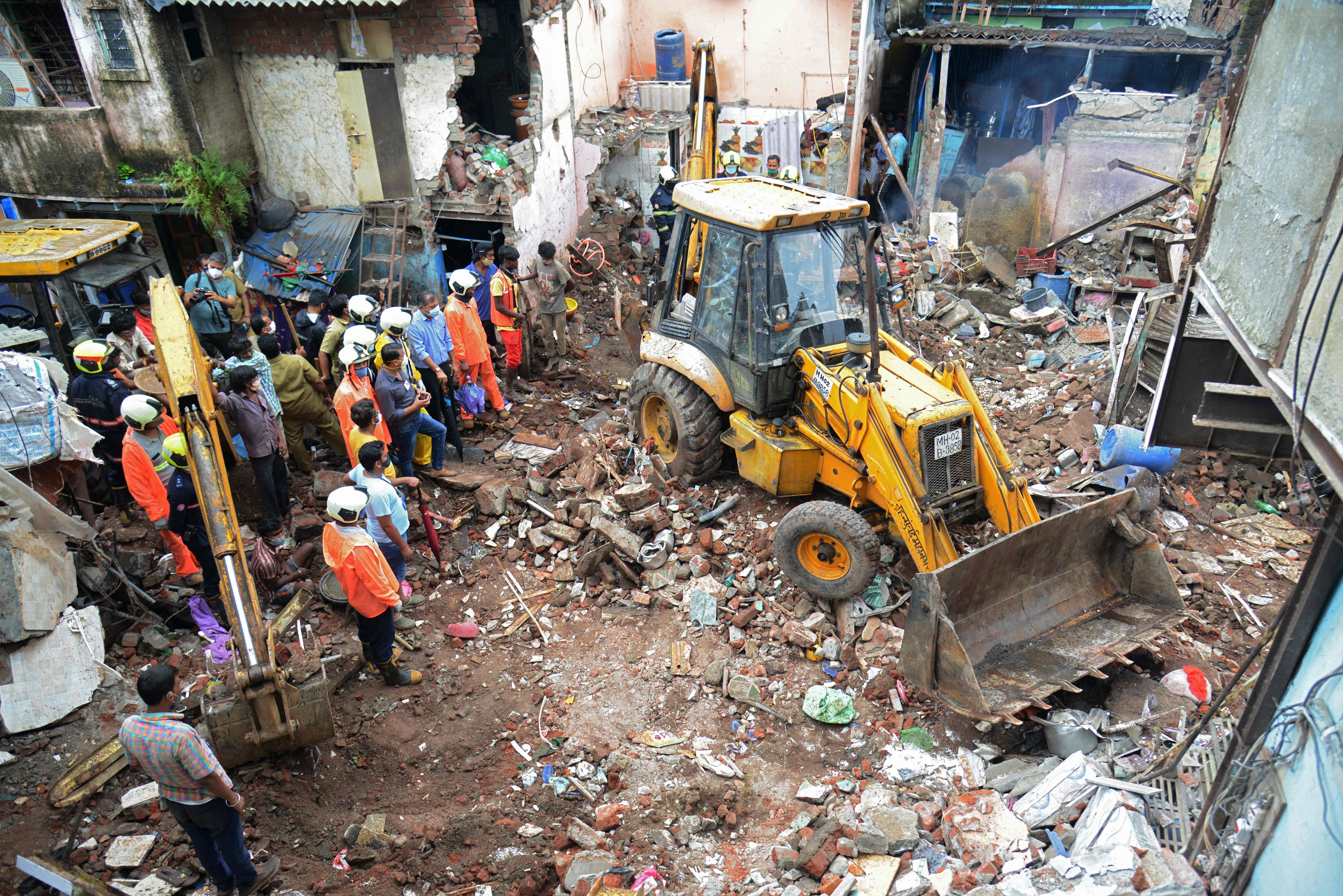 Civil authority and rescue personnel search for survivors in the debris of a building that collapsed following heavy monsoon rains, in Mumbai on June 10, 2021.