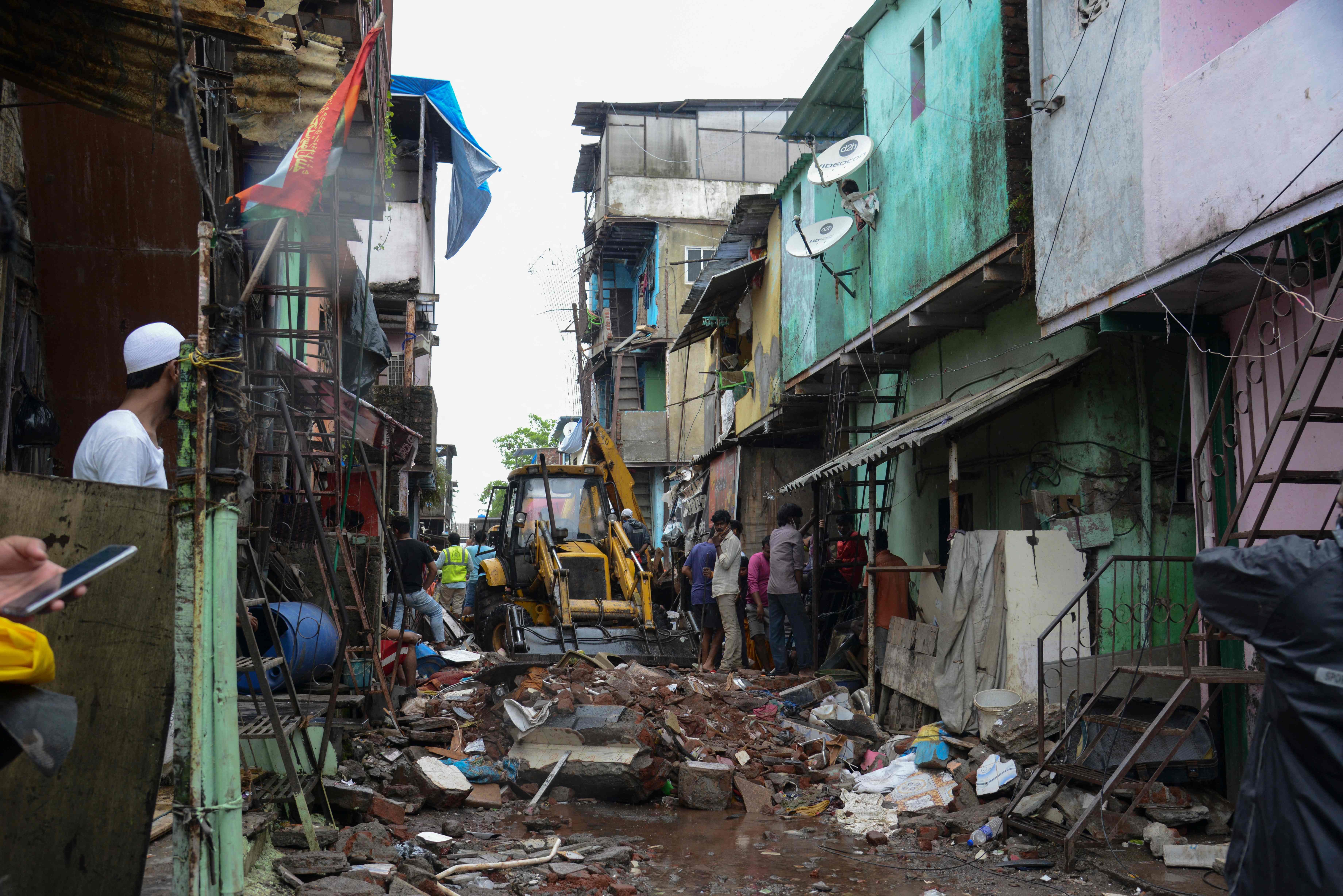 Civil authority and rescue personnel search for survivors in the debris of a building that collapsed following heavy monsoon rains, in Mumbai on June 10, 2021.