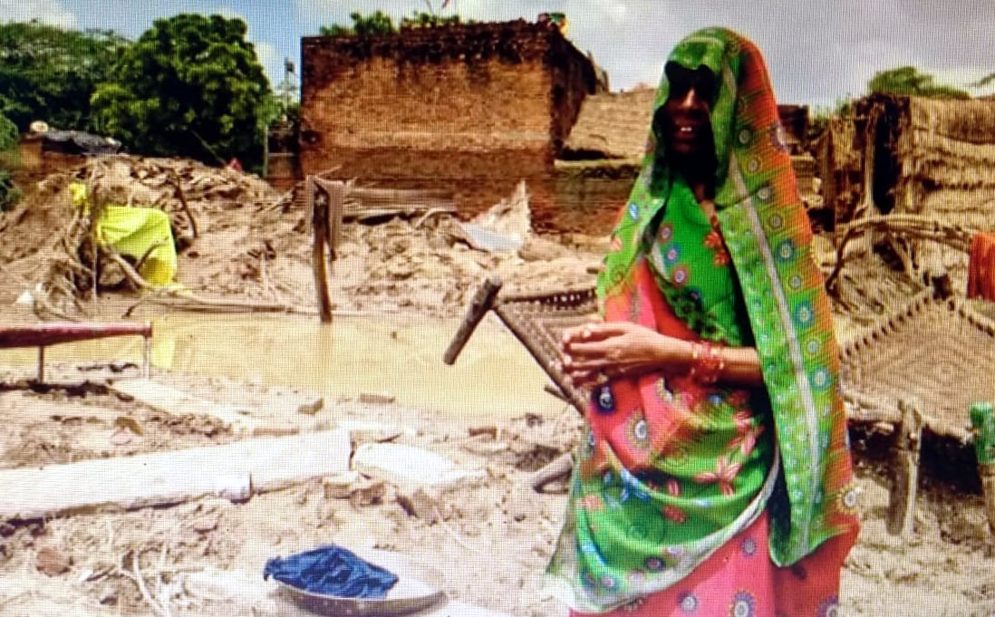A woman stands in front of her damaged house  | FP 