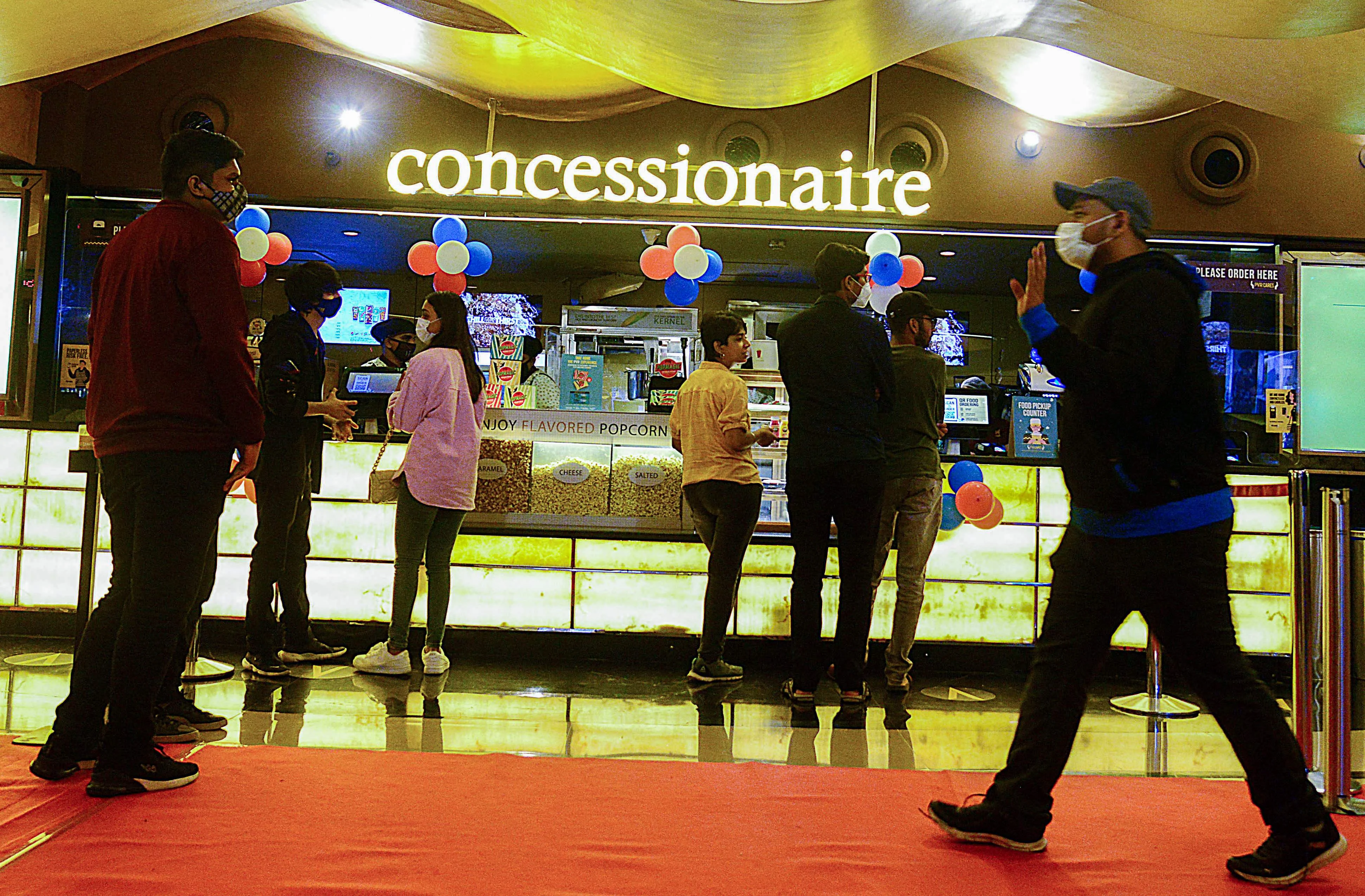 Cinema-goers queue up to buy snacks during intermission time at a cinema theatre in Mumbai on October 22, 2021