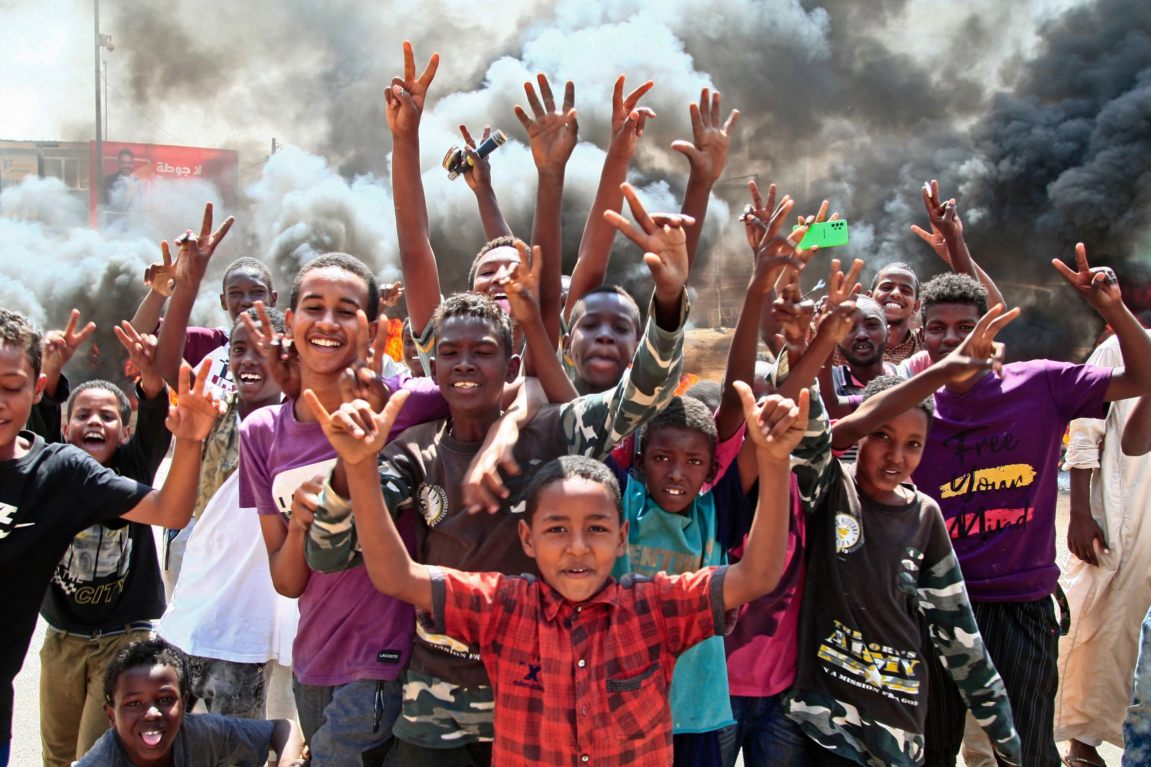 Sudanese youths flash victory signs by a roadblock made of buring tyres in the capital Khartoum, on October 26, 2021, as they protest a military coup that overthrew the transition to civilian rule.