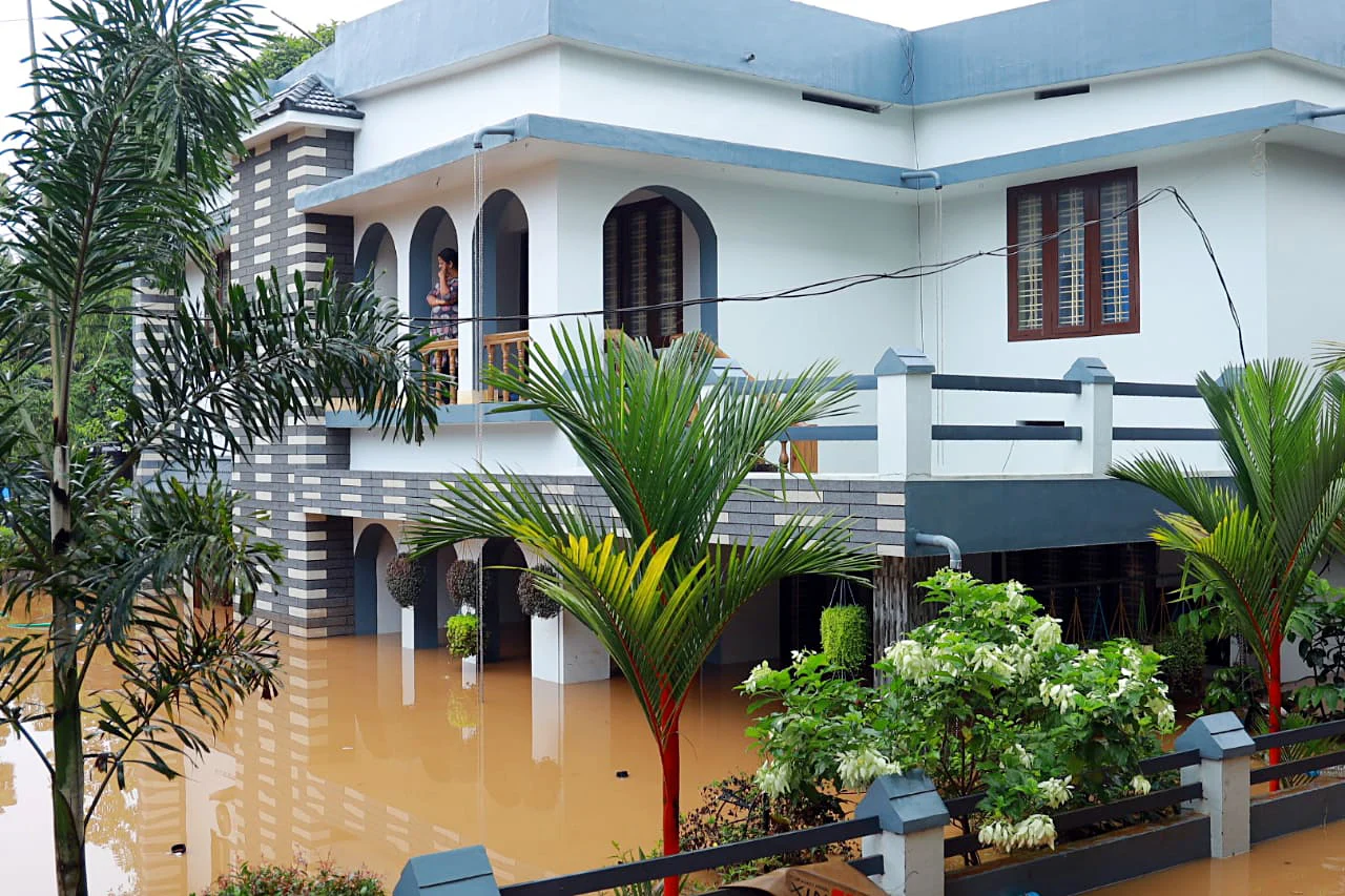 A women stands on a balcony of a house submerged in flood water following incessant rainfall, in Mallappally on Sunday.
