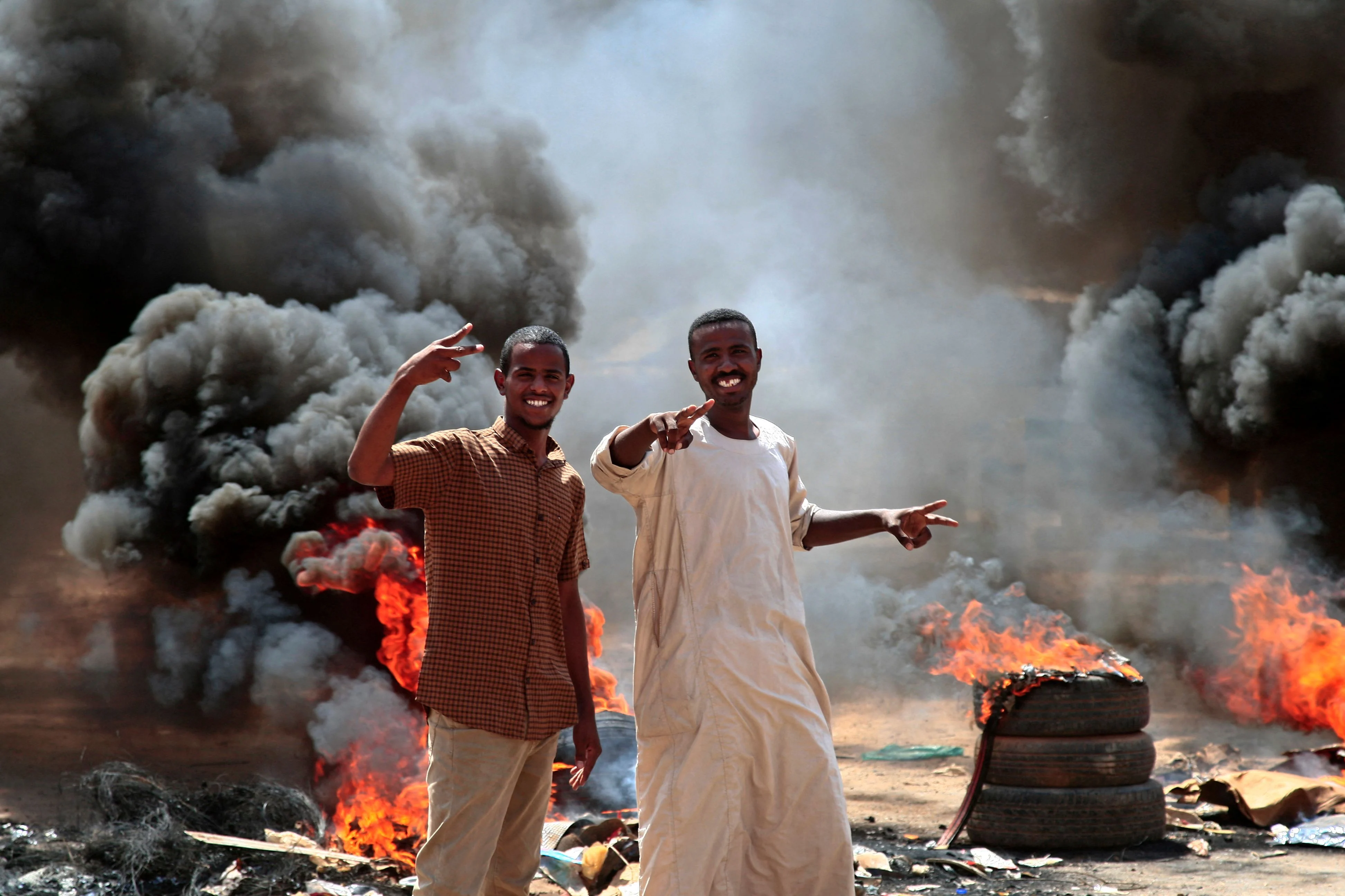 Sudanese demonstrators flash victory signs by a roadblock made of buring tyres in the capital Khartoum, on October 26, 2021, as they protest a military coup that overthrew the transition to civilian rule.