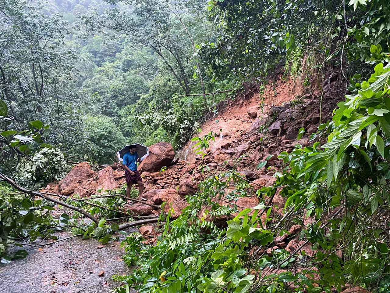 A man walks over debris triggered by a landslide at a flood-affected area, at Meloram village, in Kottayam on Sunday.
