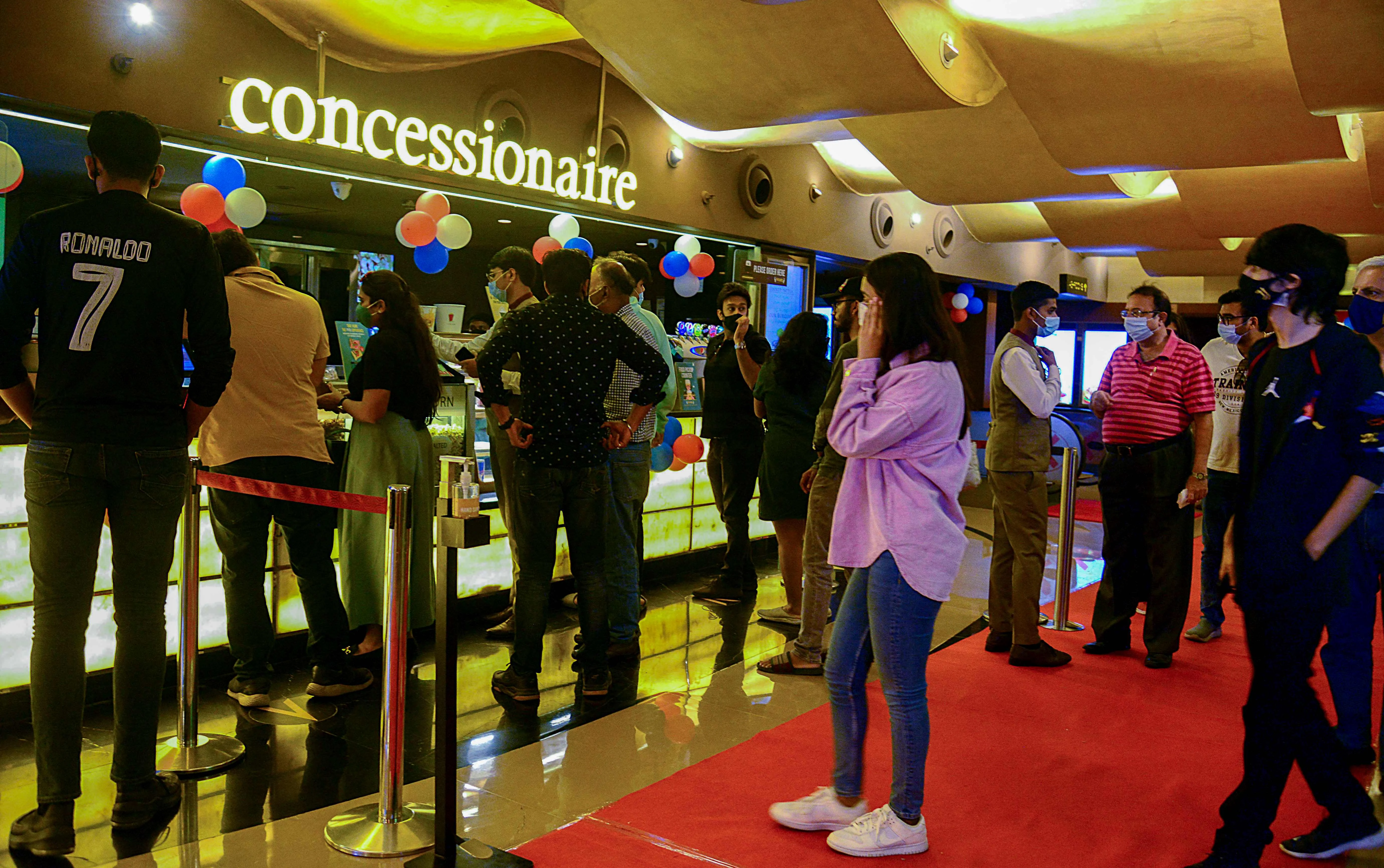 People wait in line to buy snacks at a cinema theatre in Mumbai