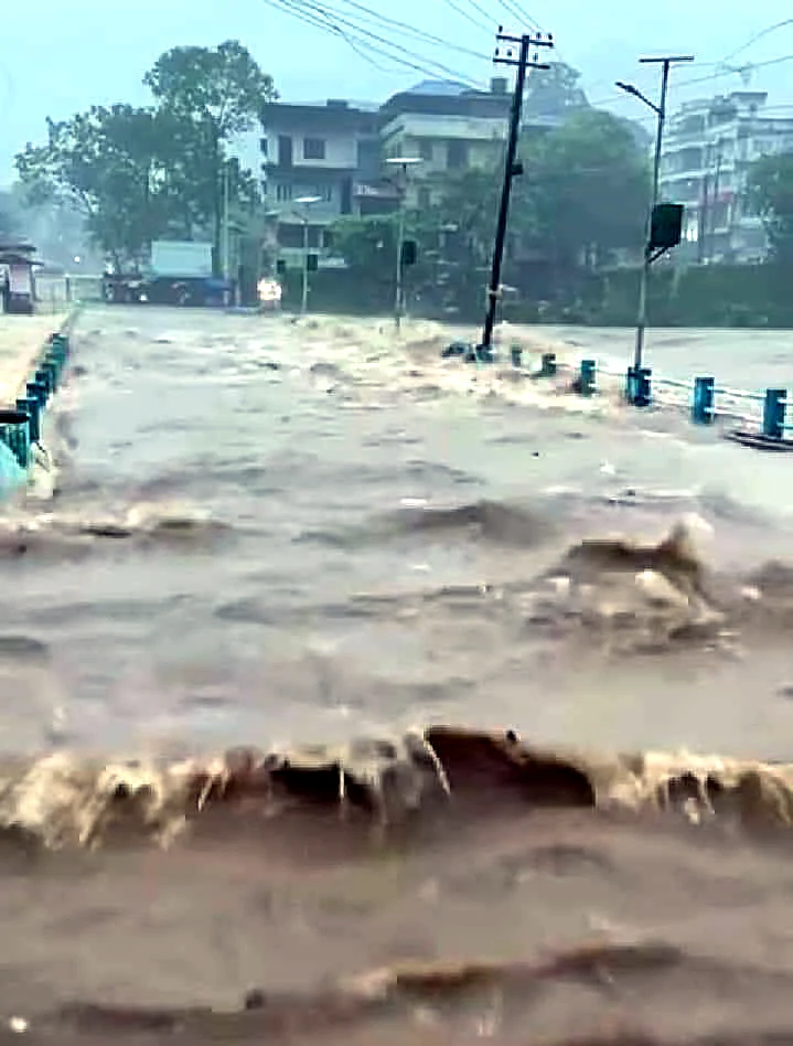 Flood water gushes through low-lying areas triggered by incessant rains, in Kottayam on Sunday.