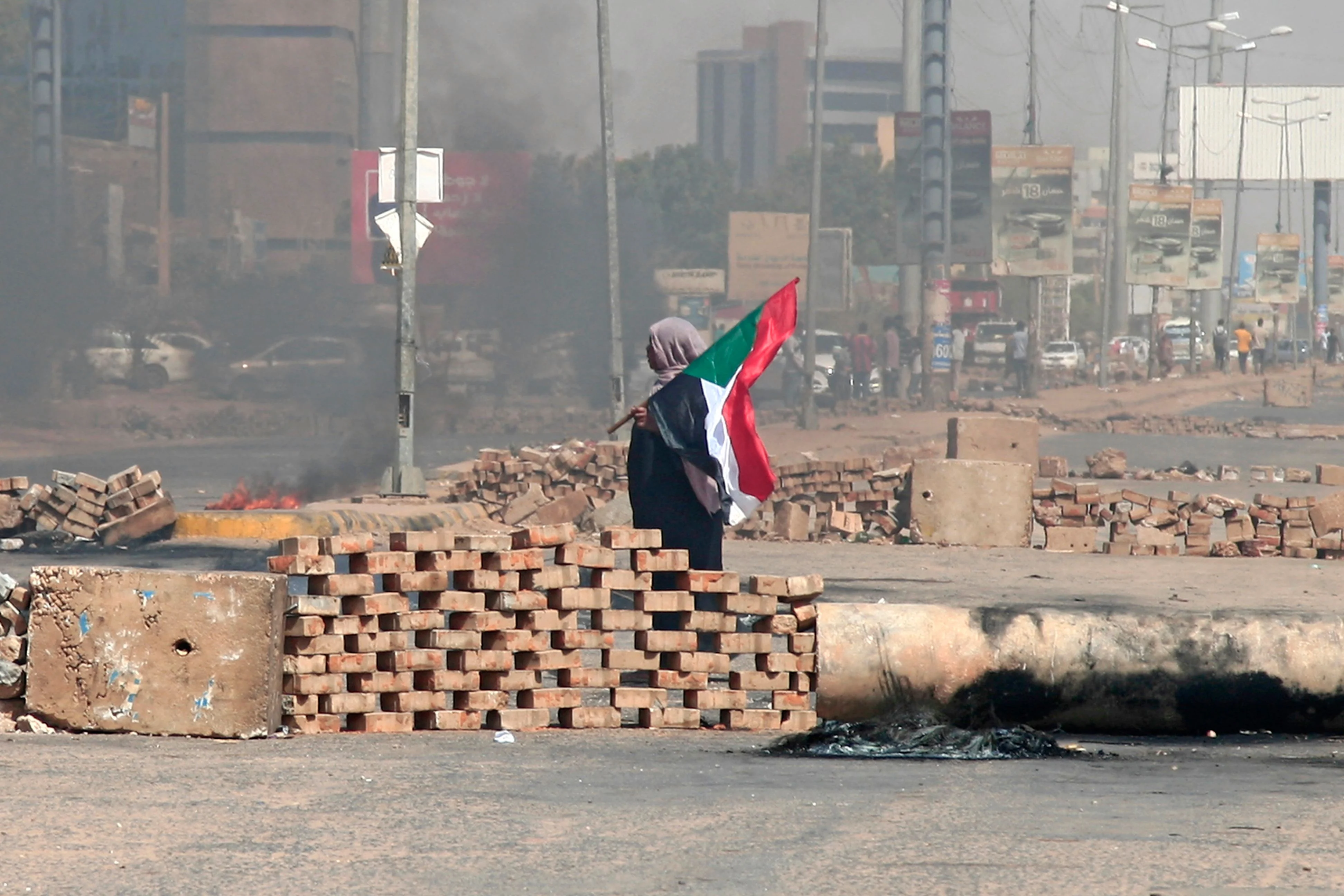 A Sudanese demonstrator carrying a national flag walks by roadblocks set up by protesters on a street in the capital Khartoum, on October 26, 2021, to denounce a military coup that overthrew the transition to civilian rule.