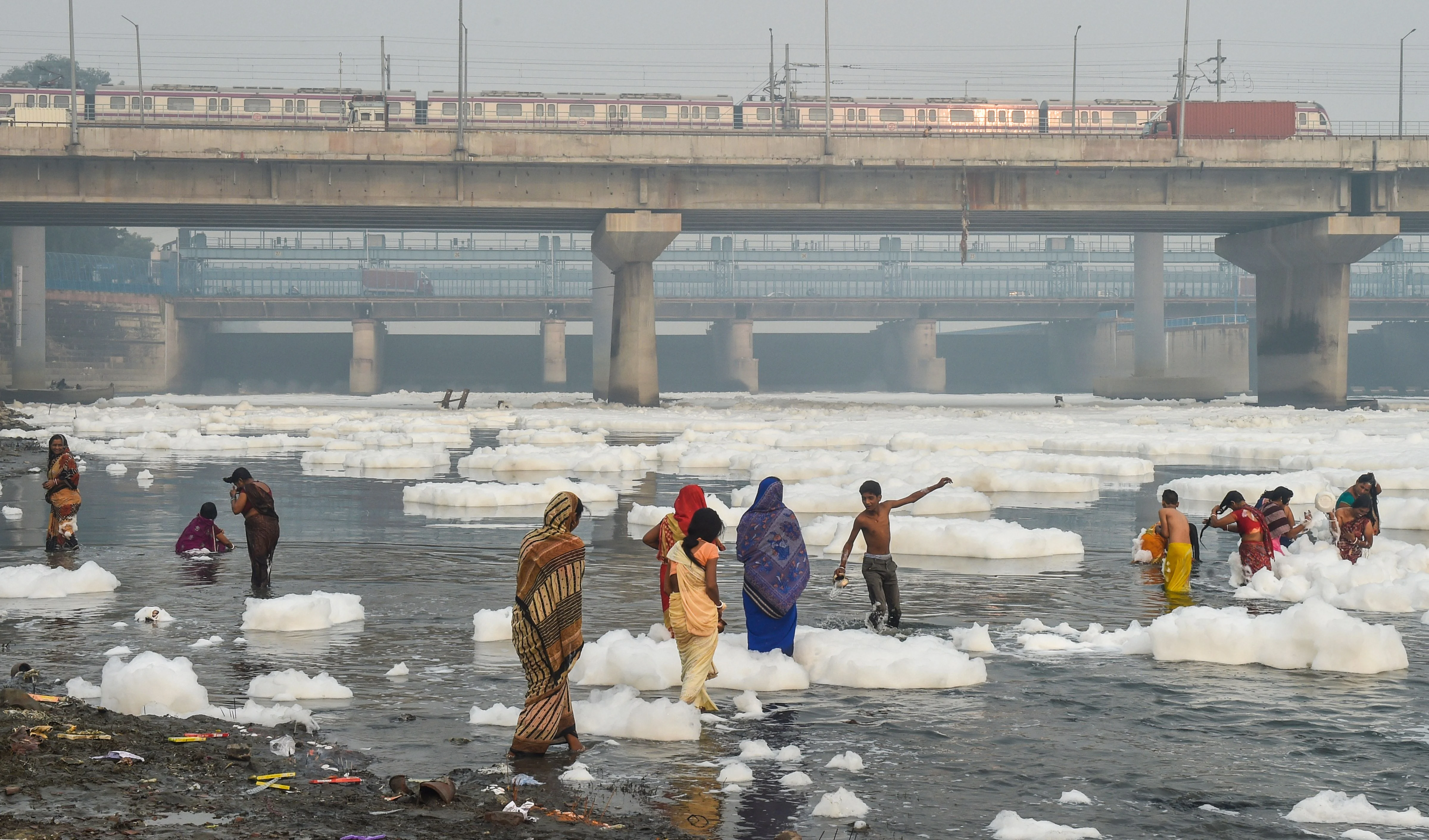 Women devotees take bath as part of the ritual of four days long Chhath Puja celebration, as toxic form floats on the surface of polluted Yamuna river at Kalindi Kunj, in New Delhi, Sunday, Nov. 7, 2021.