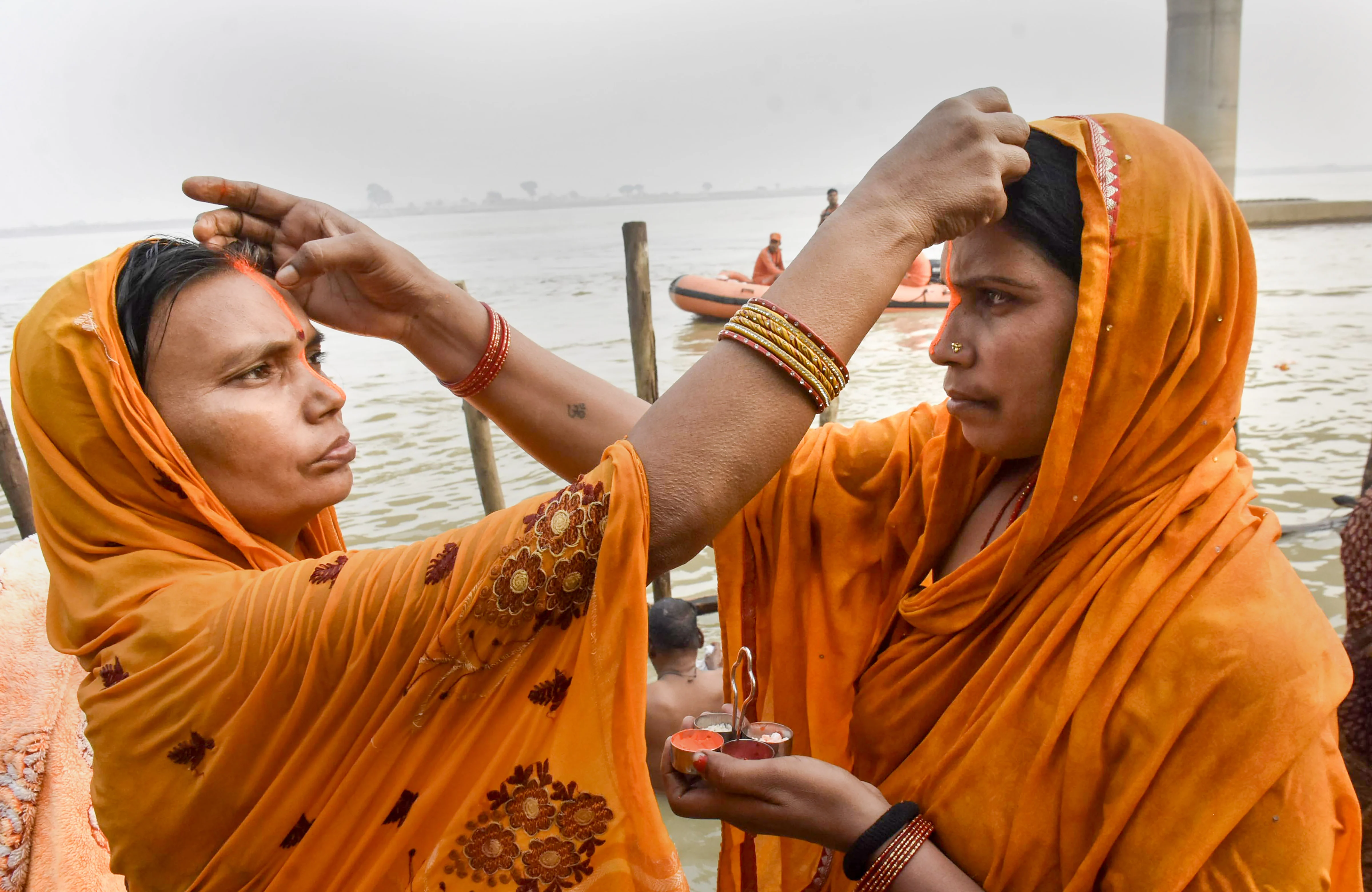 Hindu devotees apply vermillion to each other while taking bath in the holy Ganga river on the occasion of the Chhath Puja festival in Patna, Monday, Nov. 8, 2021