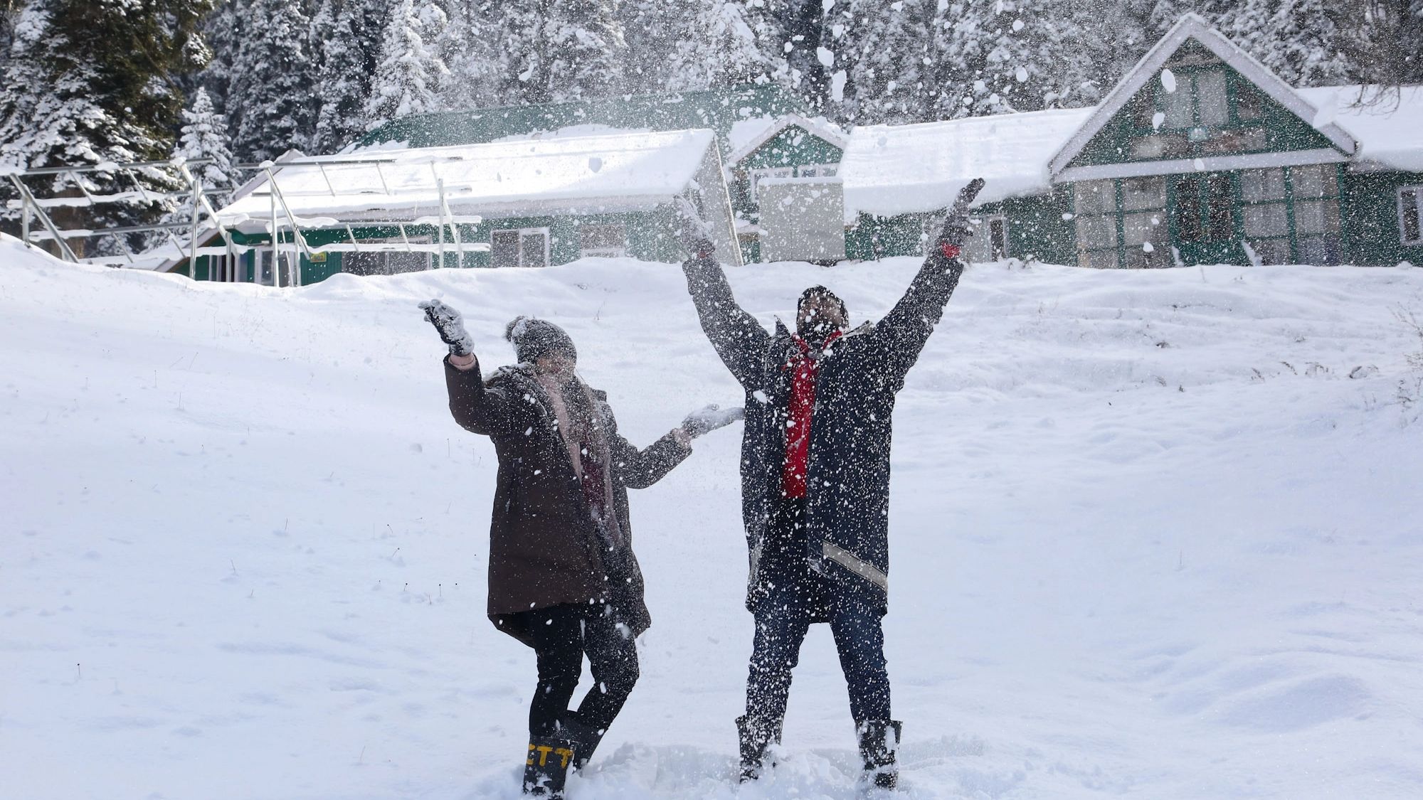 Tourist couple play with snow during a sunny winter day at snow covered ski resort Gulmarg after the fresh snowfall on December 07, 2021.