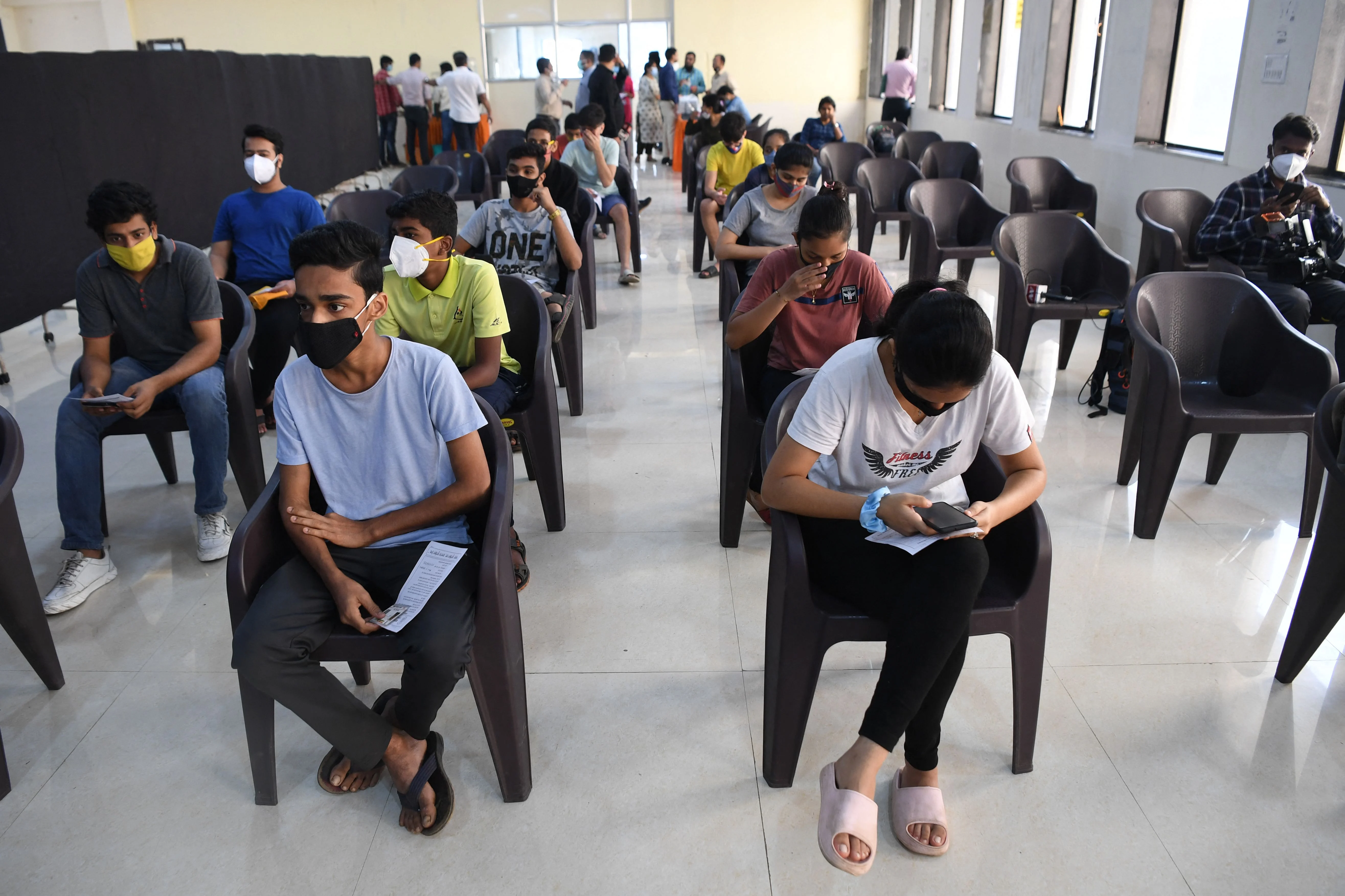 Youths wait for their turn to get inoculated with a dose of Covid-19 coronavirus vaccine during a vaccination drive for people in the 15-18 age group, in Mumbai on January 3, 2022.