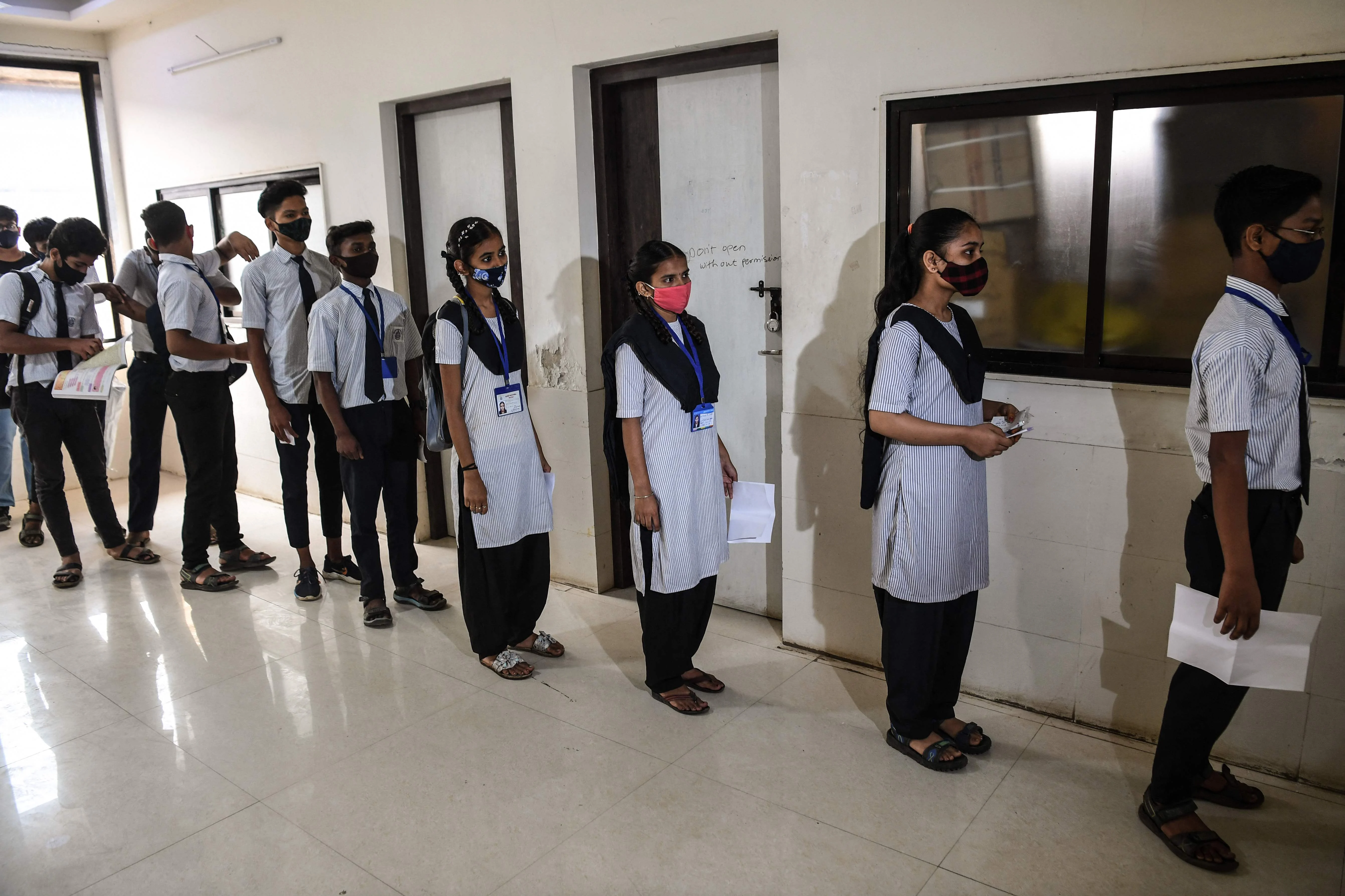 Youths stand in a queue as they wait for their turn to get inoculated with a dose of Covid-19 coronavirus vaccine during a vaccination drive for people in the 15-18 age group, in Mumbai on January 3, 2022