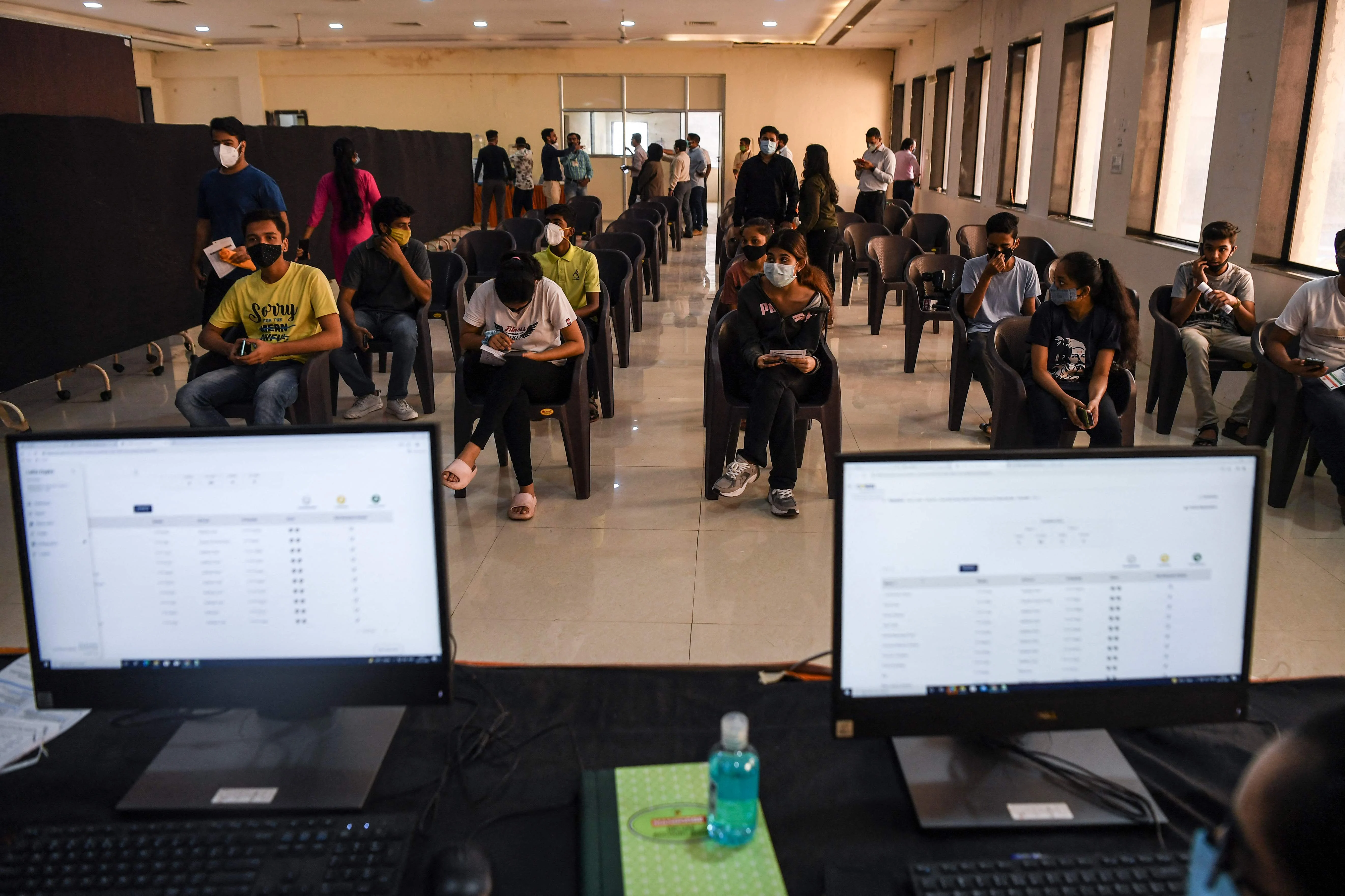 Youths wait for their turn to get inoculated with a dose of Covid-19 coronavirus vaccine during a vaccination drive for people in the 15-18 age group, in Mumbai on January 3,