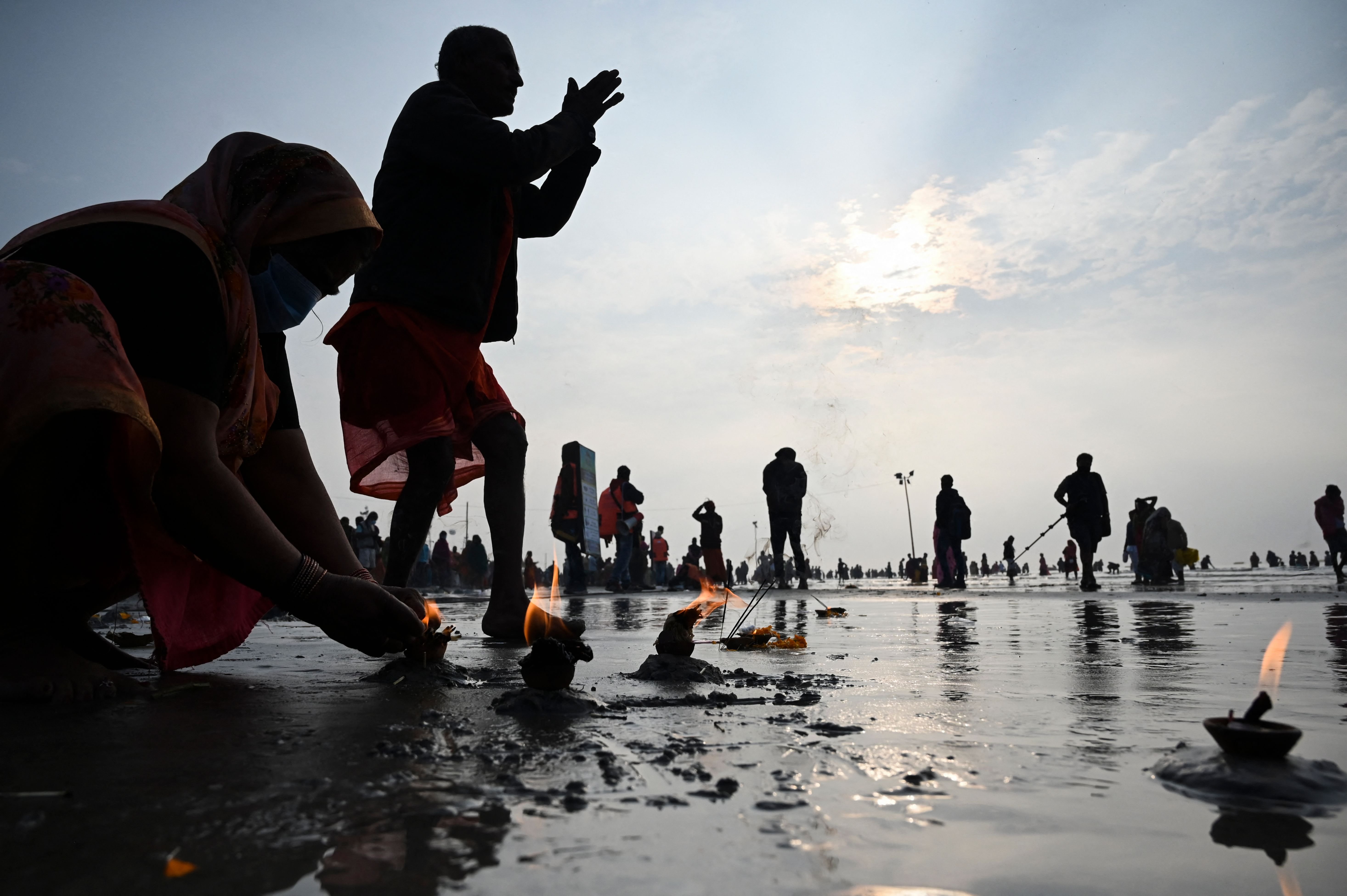 TOPSHOT - Pilgrims perform rituals as they pray at the beach during the Hindu religious festival of Gangasagar Mela on Sagar Island, some 150 kilometers south of Kolkata, West Bengal, on January 13, 2022.