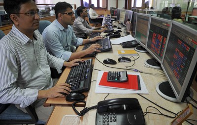 Stock traders monitor share prices on their computers during intra-day trade at a brokerage house in Mumbai | 