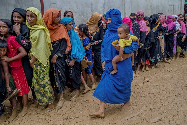 Newly arrived Rohingya women wait for their turn to collect building material for their shelters distributed by aid agencies in Kutupalong refugee camp, Bangladesh. Newly arrived Rohingya women wait for their turn to collect building material for their shelters distributed by aid agencies in Kutupalong refugee camp, Bangladesh.