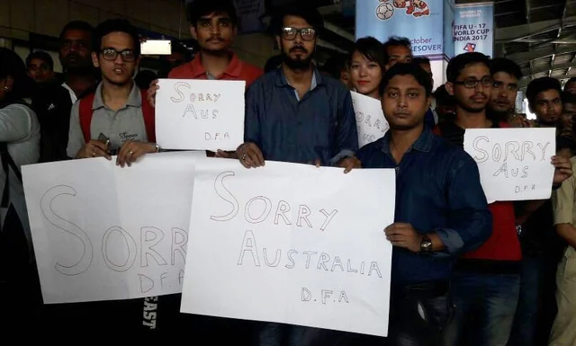 People stand with placards reading “Sorry Australia” at Lokpriya Gopinath Bordoloi International Airport in Guwahati after a stone was thrown at their bus. People stand with placards reading “Sorry Australia” at Lokpriya Gopinath Bordoloi International Airport in Guwahati after a stone was thrown at their bus.