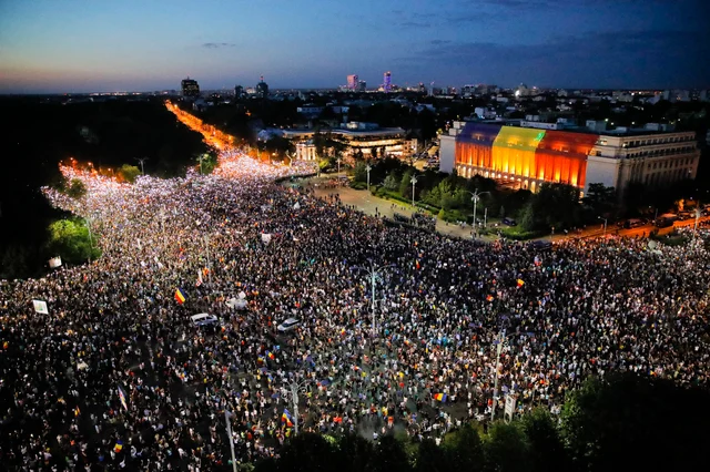 People shine the lights of their mobile phones during protests outside the government headquarters, seen at the right, in Bucharest, Romania. People shine the lights of their mobile phones during protests outside the government headquarters, seen at the right, in Bucharest, Romania.