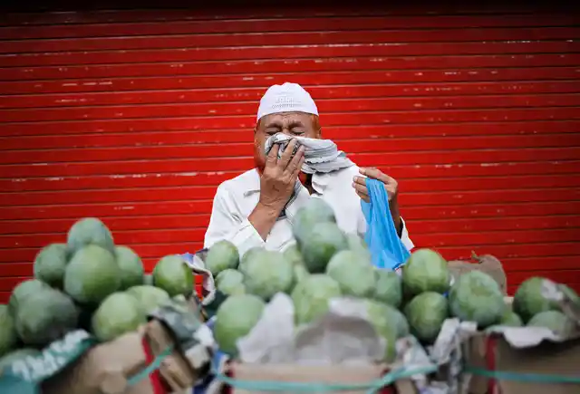<!--StartFragment-->A vendor sneezes while selling mangoes along a roadside in the old quarters of Delhi. (Photo: Reuters)<!--EndFragment-->