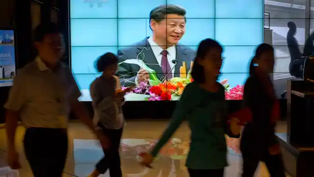 People walk past a large videoscreen showing Chinese President Xi Jinping during his trip to the United States from Chinese state broadcaster CCTV in an office building in Beijing, Friday, Sept. 25, 2015. (Photo: AP)